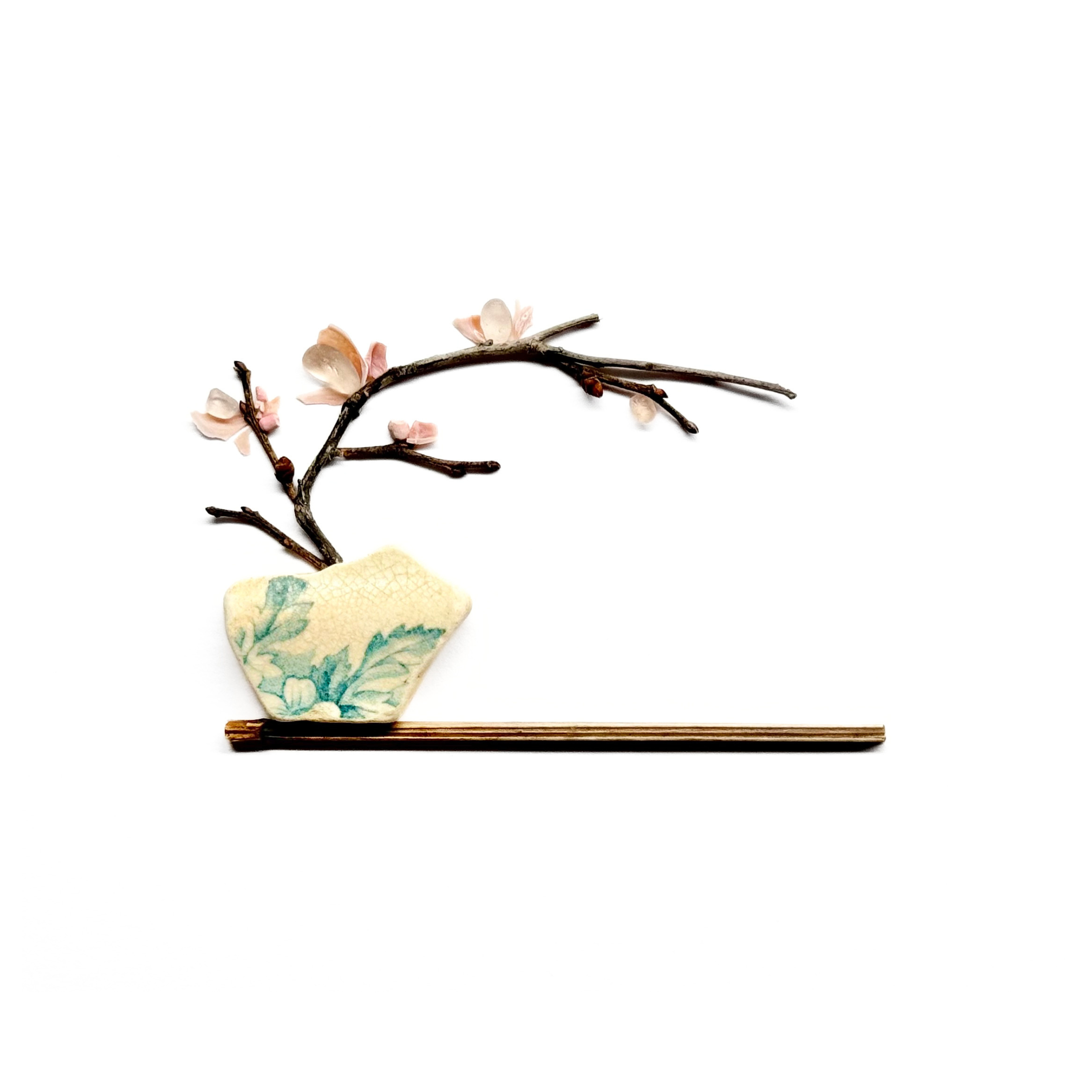 Minimalist sea glass ikebana arrangement with a cherry blossom branch, small pottery vessel, and wooden shelf.