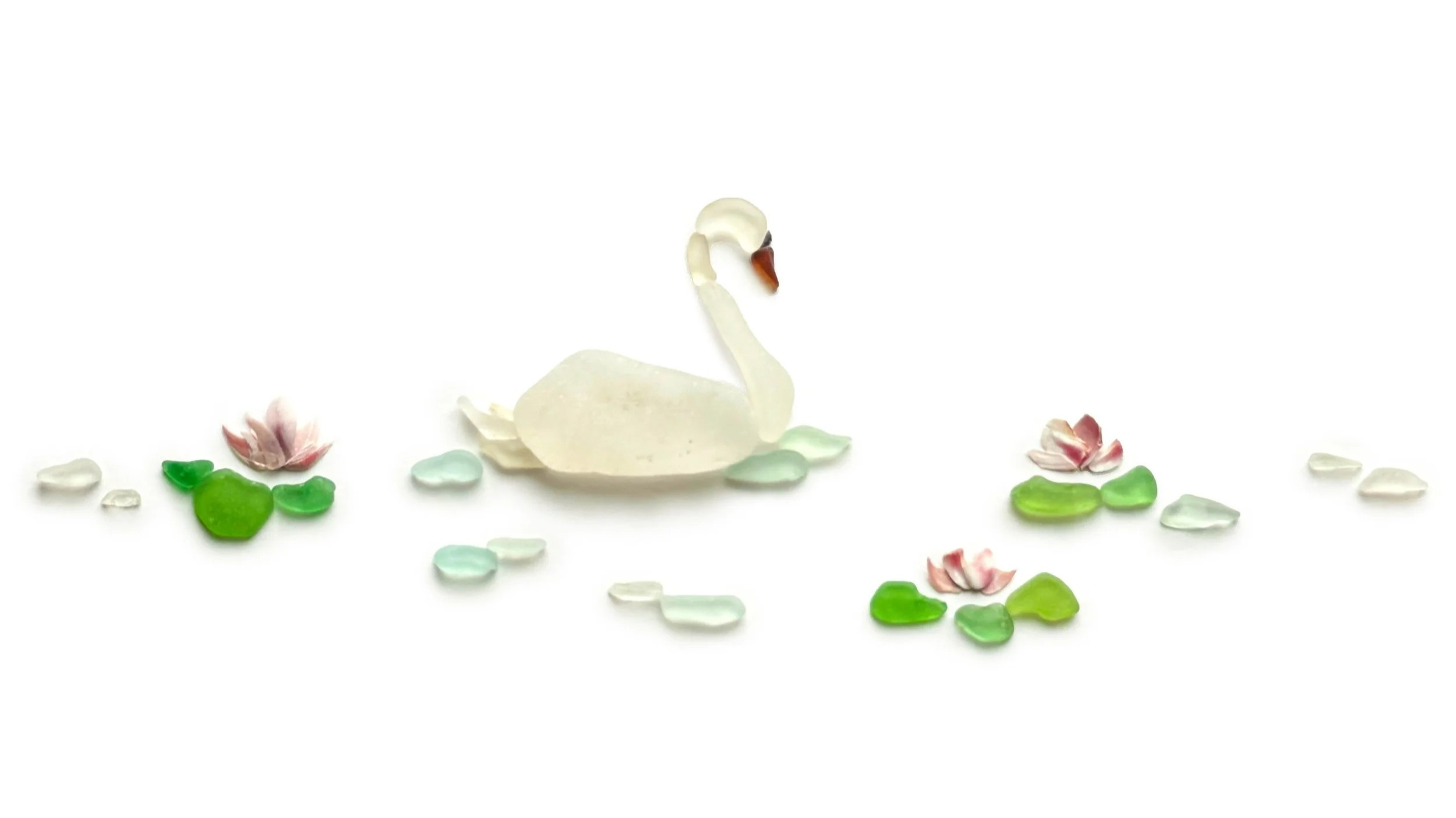 A graceful white swan glides among water lilies created from sea glass, beach stones, and coastal finds.