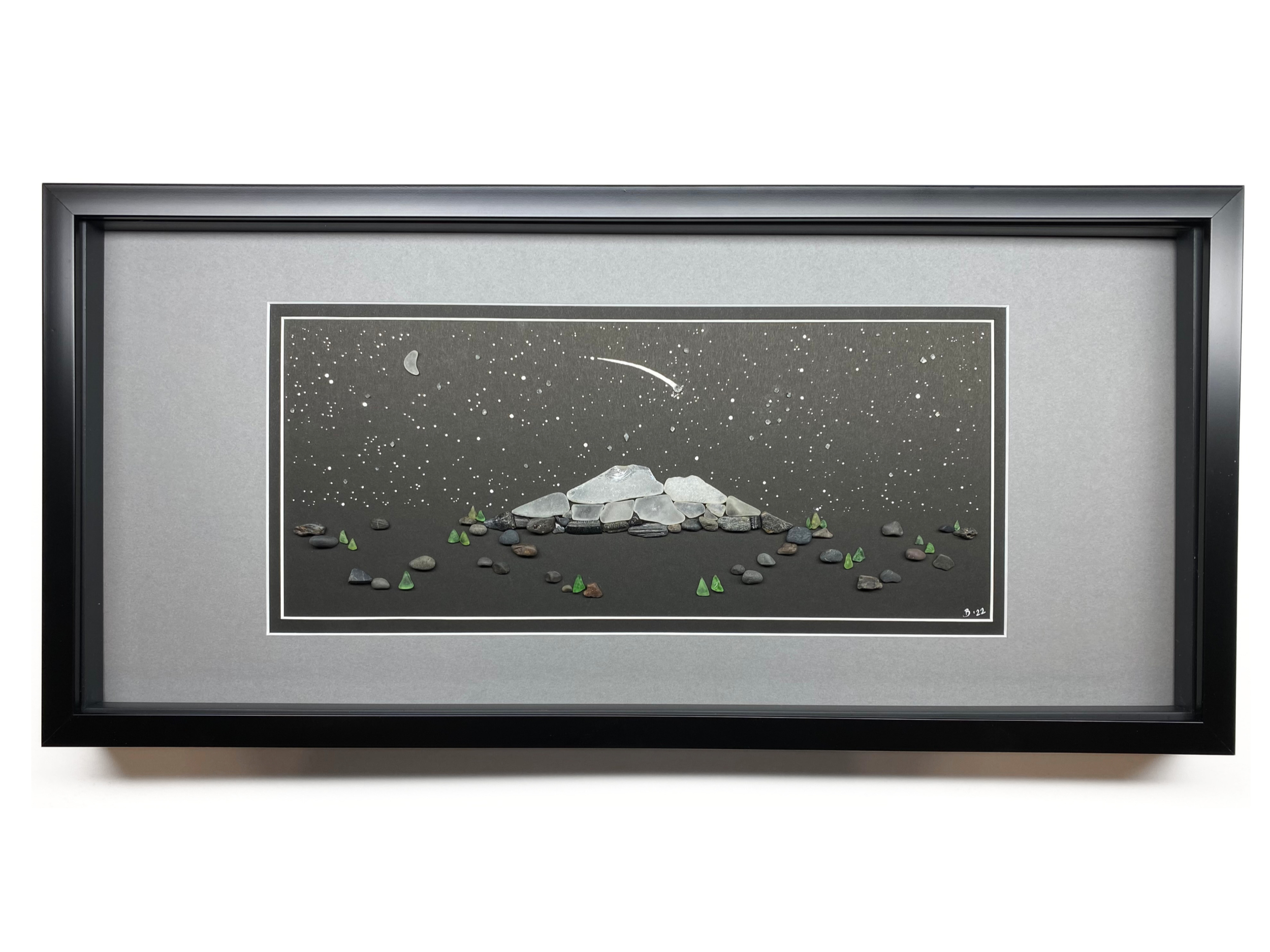 A framed mountain landscape beneath a starry night sky, created with sea glass and naturally found coastal materials.