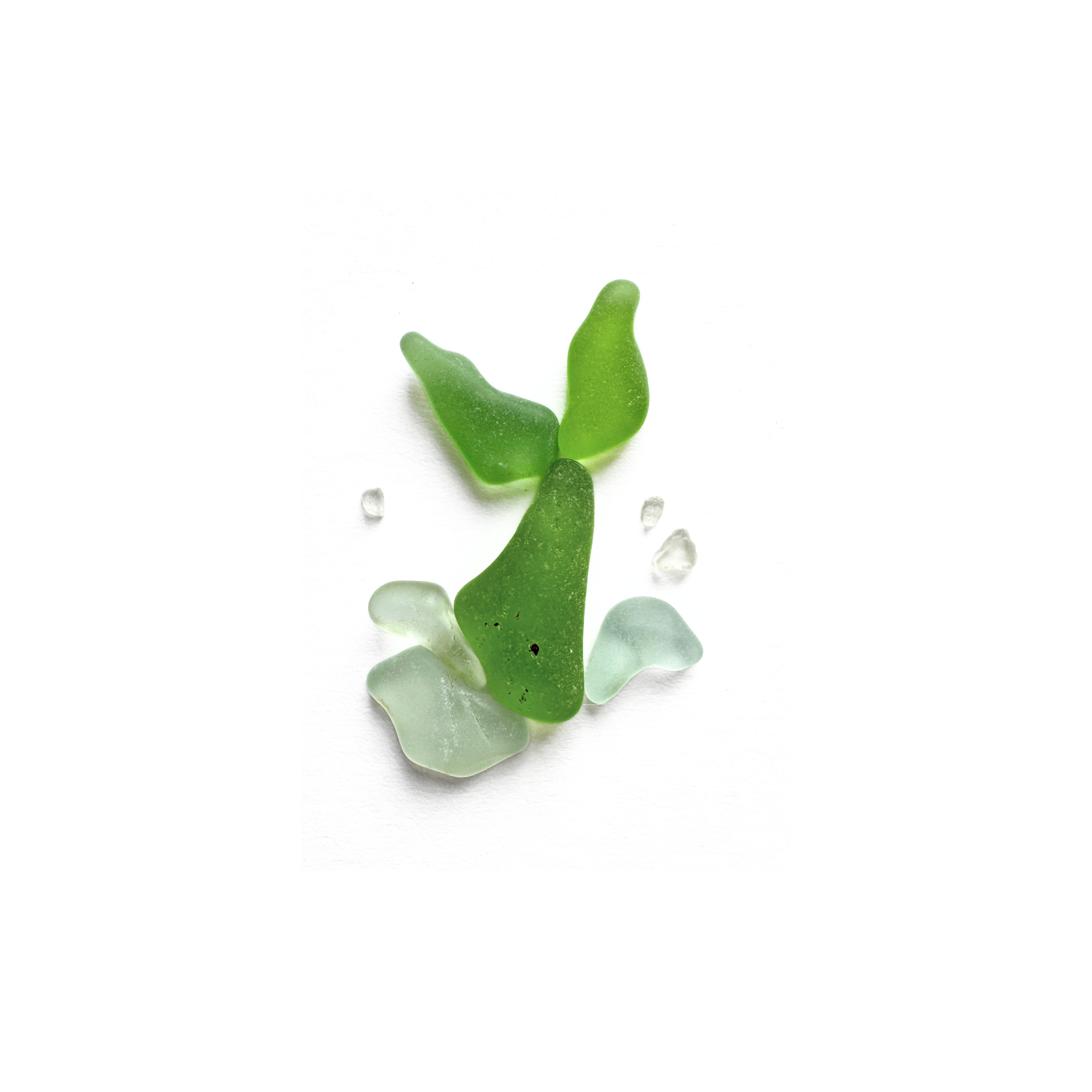 Green sea glass mermaid tail rising in a playful splash from pale aqua ocean waves.
