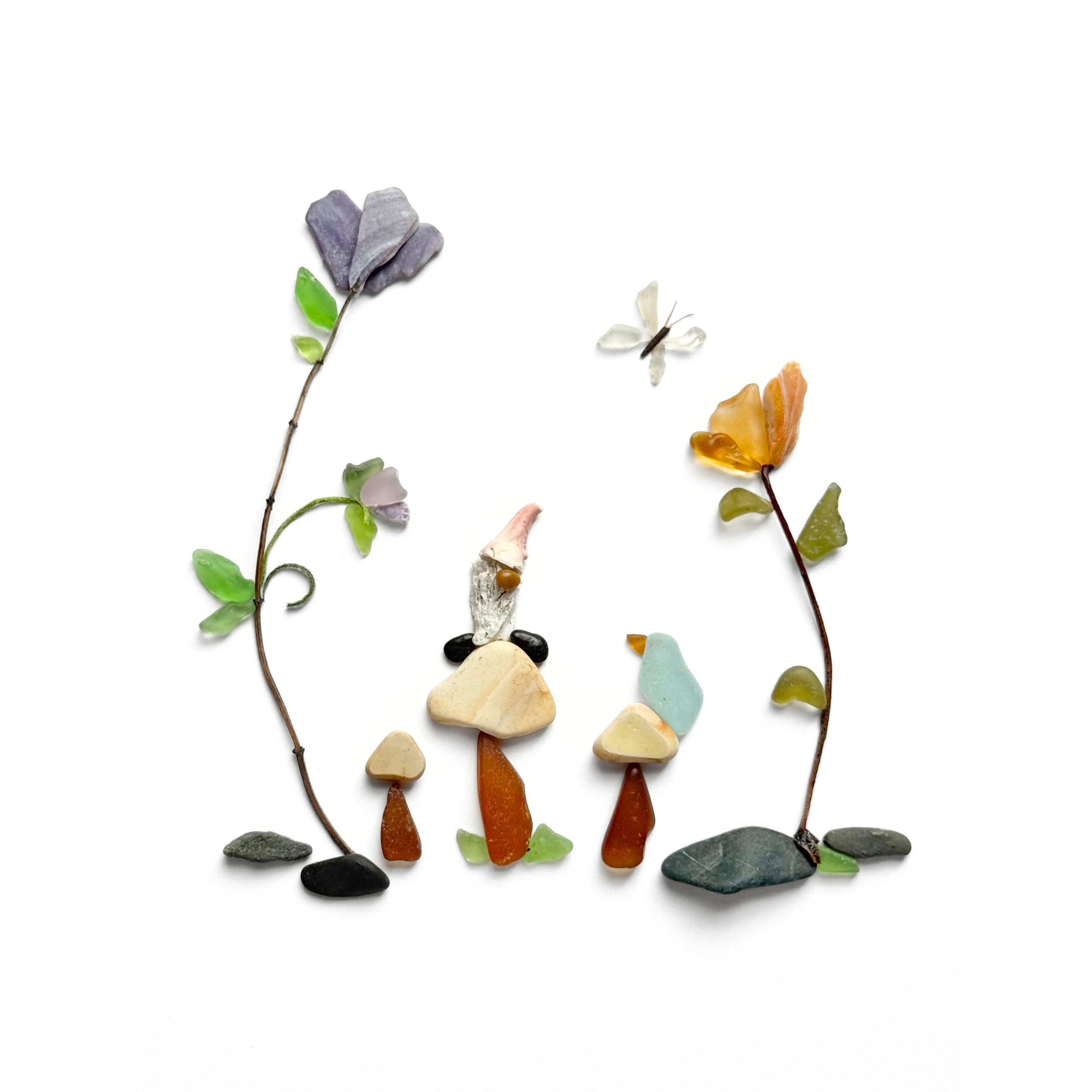A whimsical woodland gnome wanders among delicate wildflowers created with sea glass, beach stones, and preserved botanical elements.