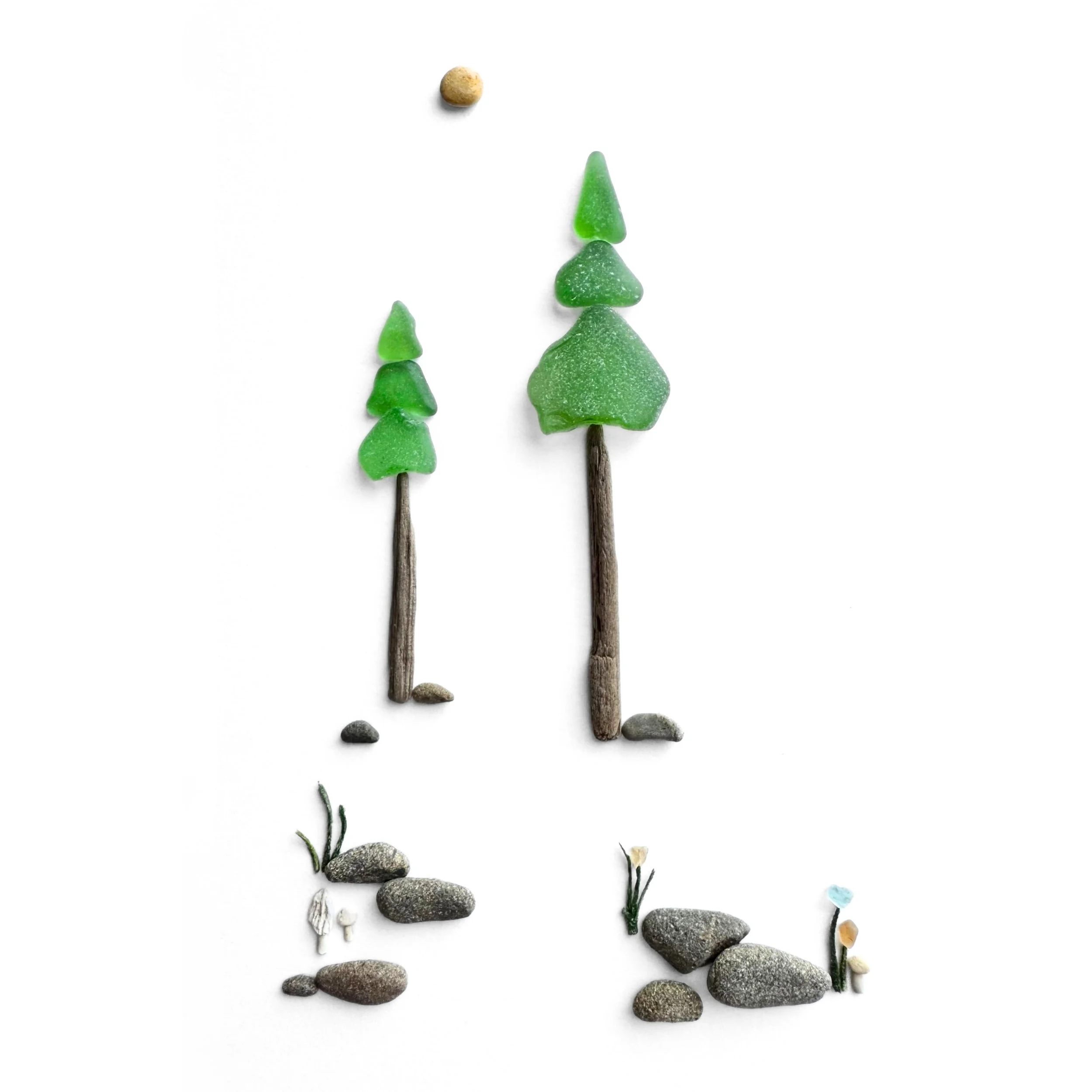 Original sea glass artwork featuring two green evergreen trees with driftwood trunks, a golden sun, and tiny mushrooms along a beach-stone path against a white background.