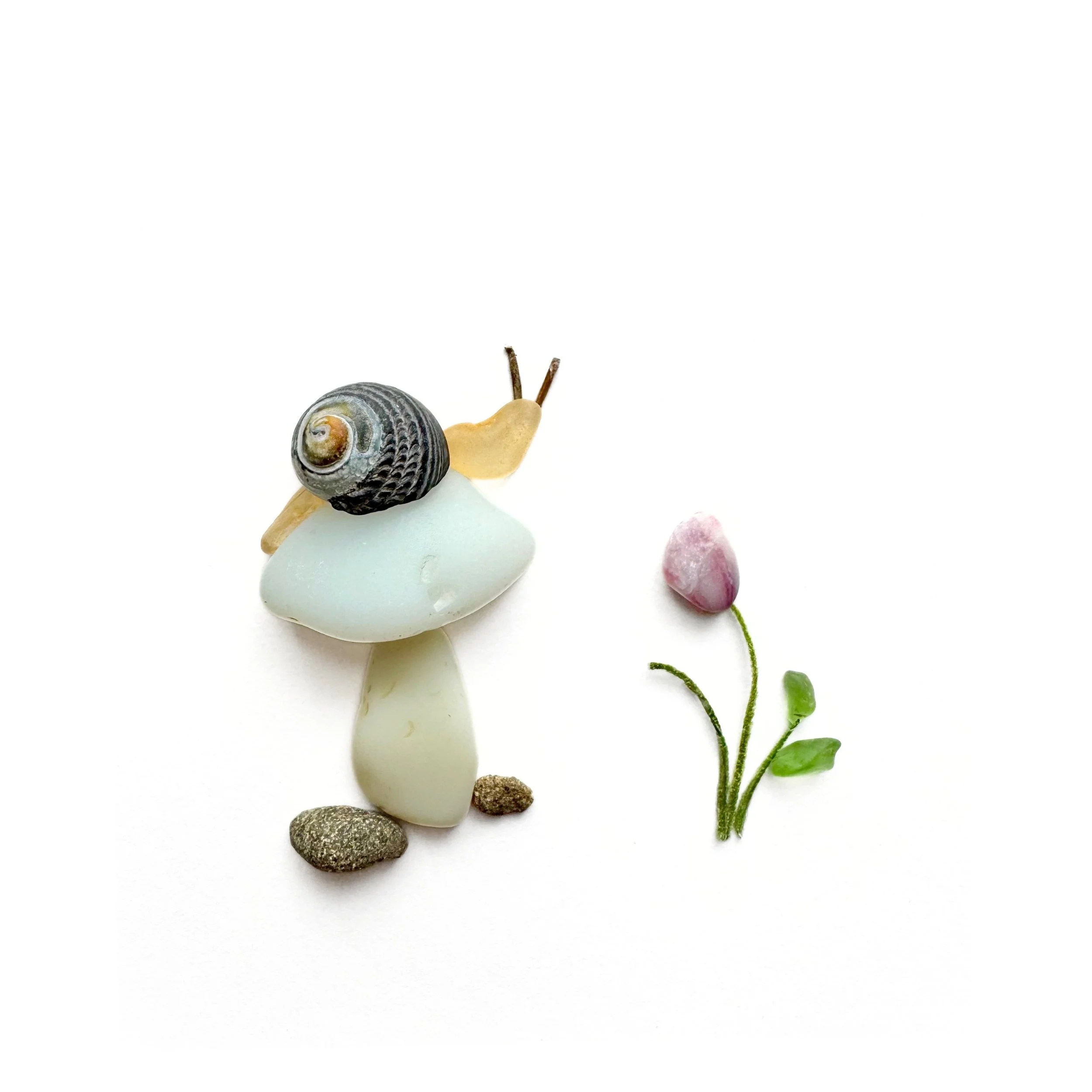 Original sea glass artwork featuring a curious snail with a dark spiral shell perched atop a pale milk glass mushroom beside a pink flower and beach pebbles against a white background.