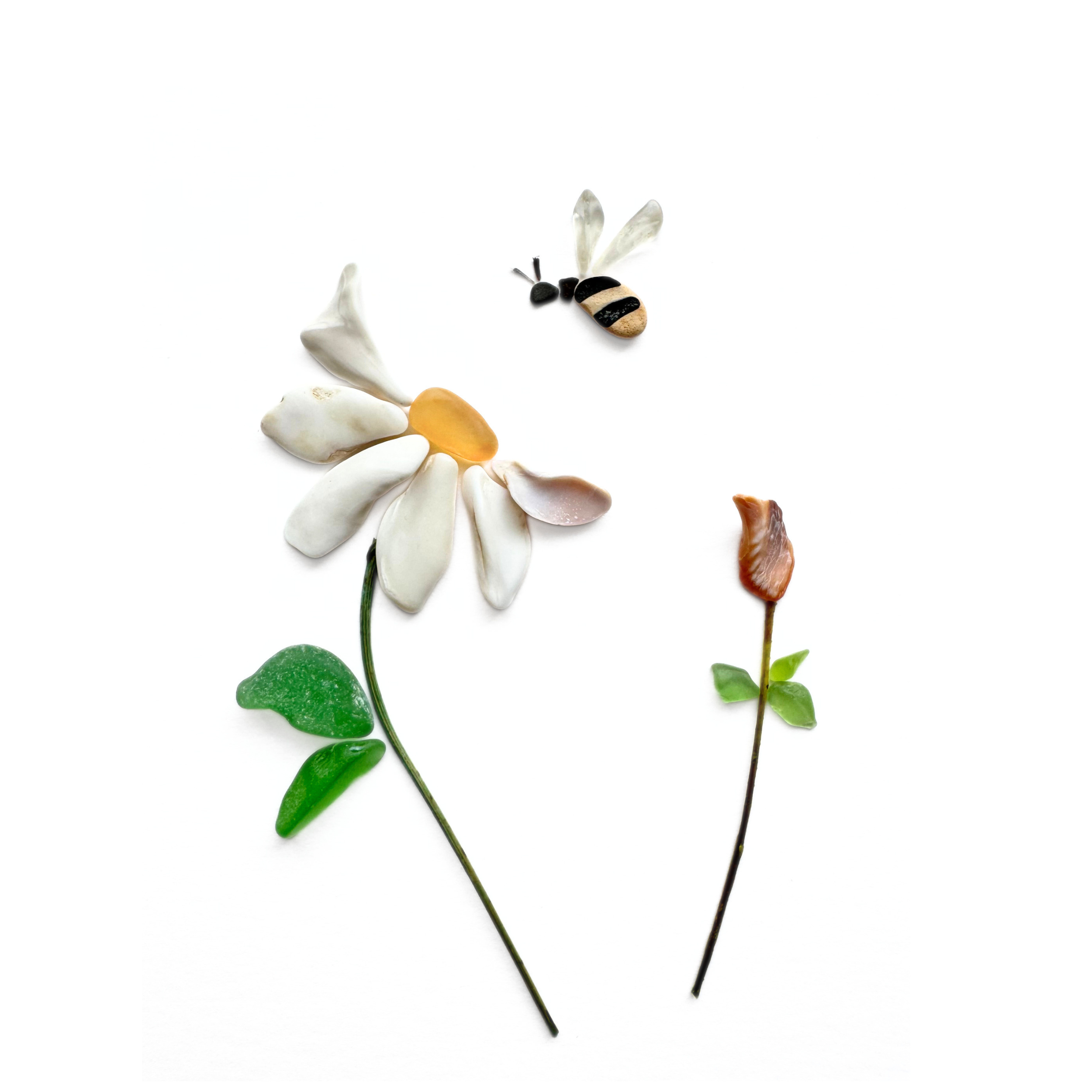 A tiny bee visits a daisy sea glass and shell flower in a delicate celebration of the garden.