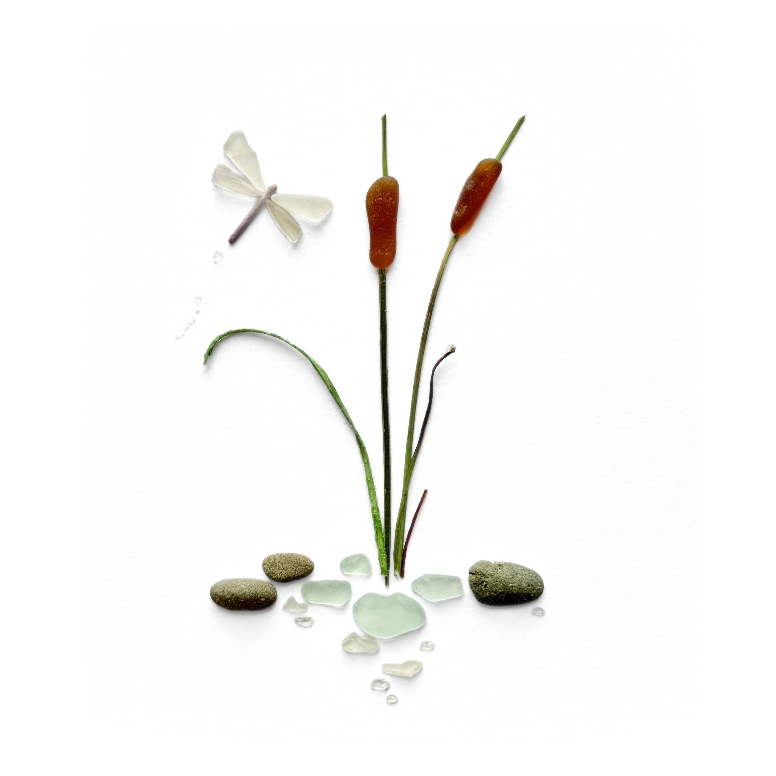 Original sea glass artwork featuring a delicate white dragonfly hovering beside two brown cattails, slender green marsh grasses, beach stones, and pale aqua sea glass against a white background.