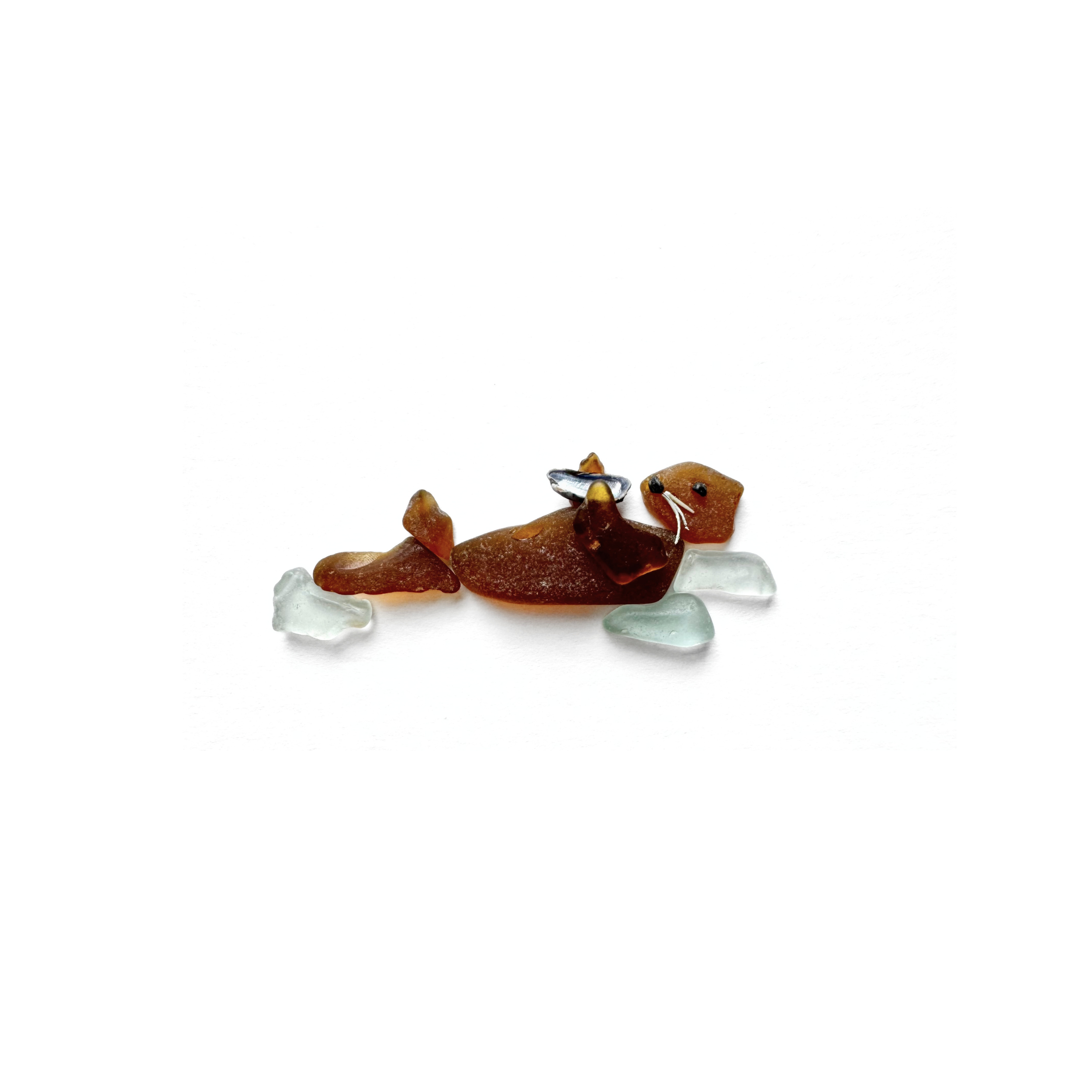 Playful brown sea glass otter floating on its back while holding a tiny mussel shell.