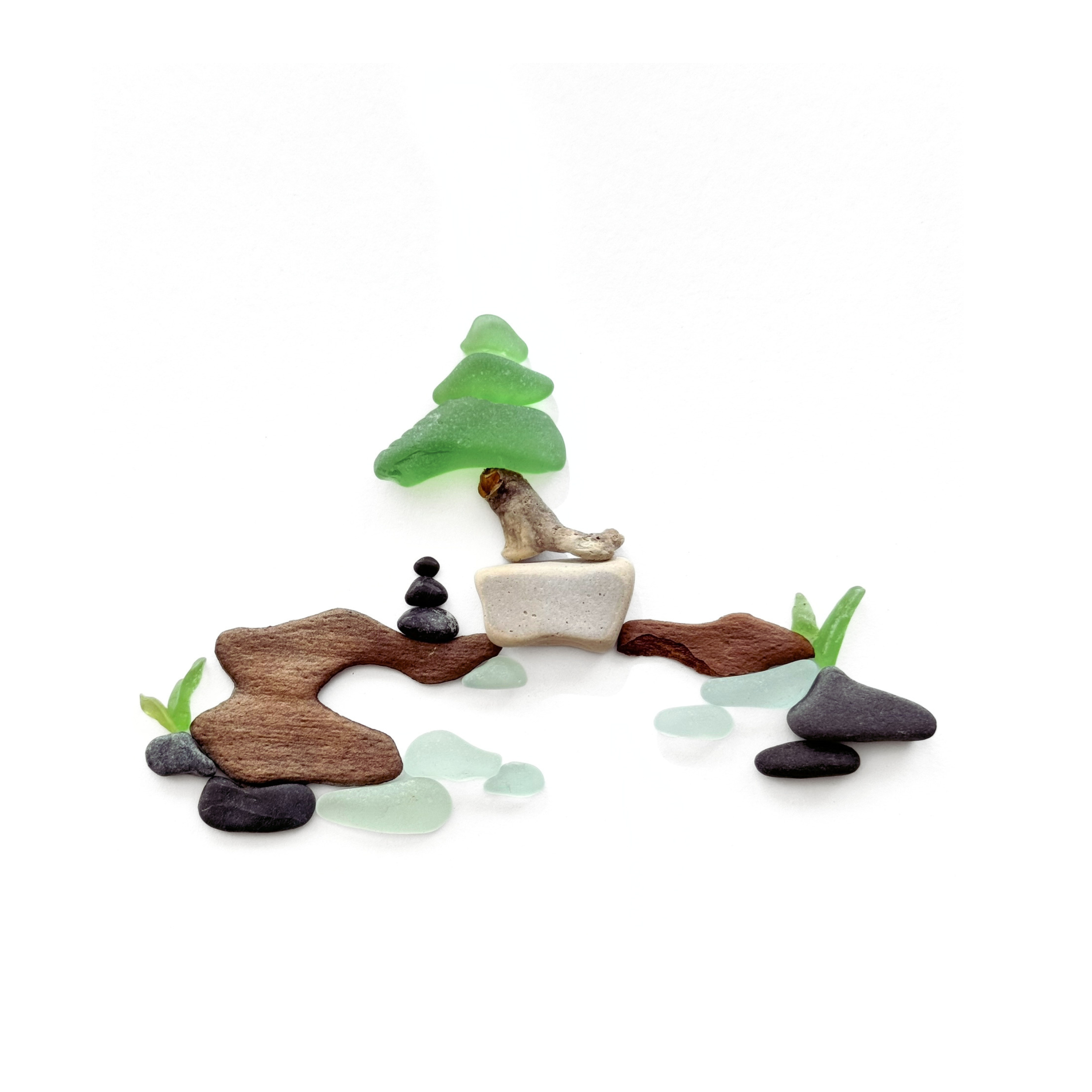 A peaceful bonsai Zen garden created with sea glass, driftwood, smooth stones, and a tiny meditating cairn stack.