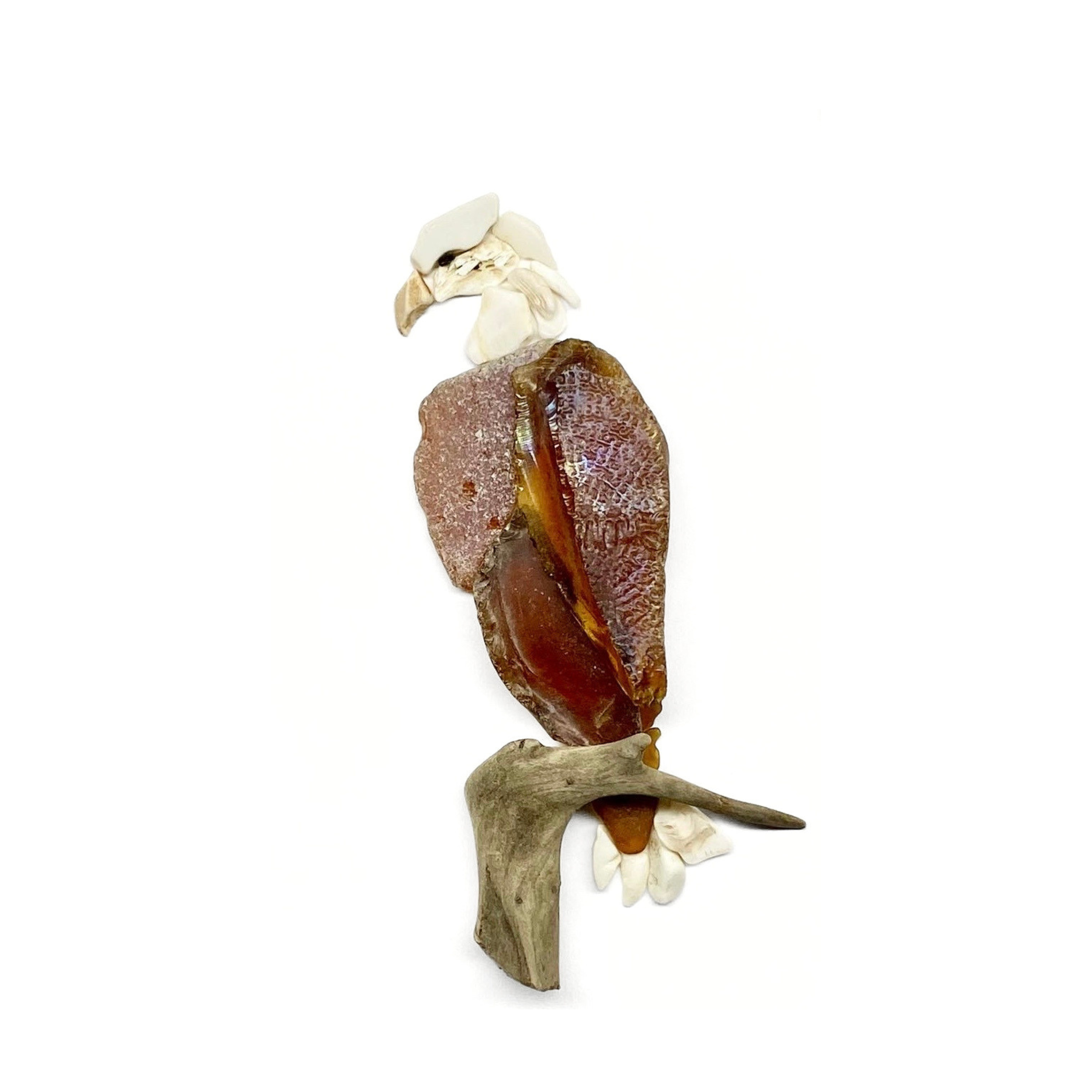 A majestic bald eagle perches on driftwood, created from richly textured sea glass and coastal finds.