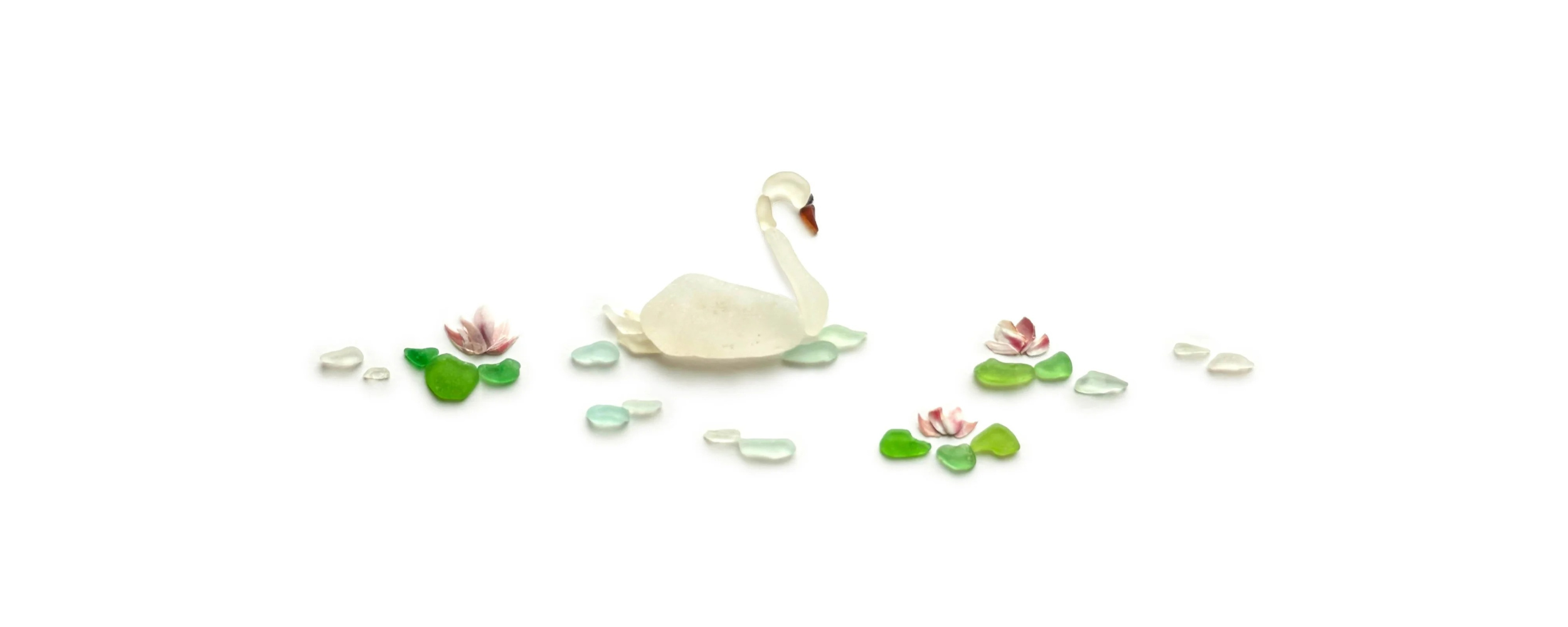Sea glass swan floating on water with lily pads and soft pink flowers