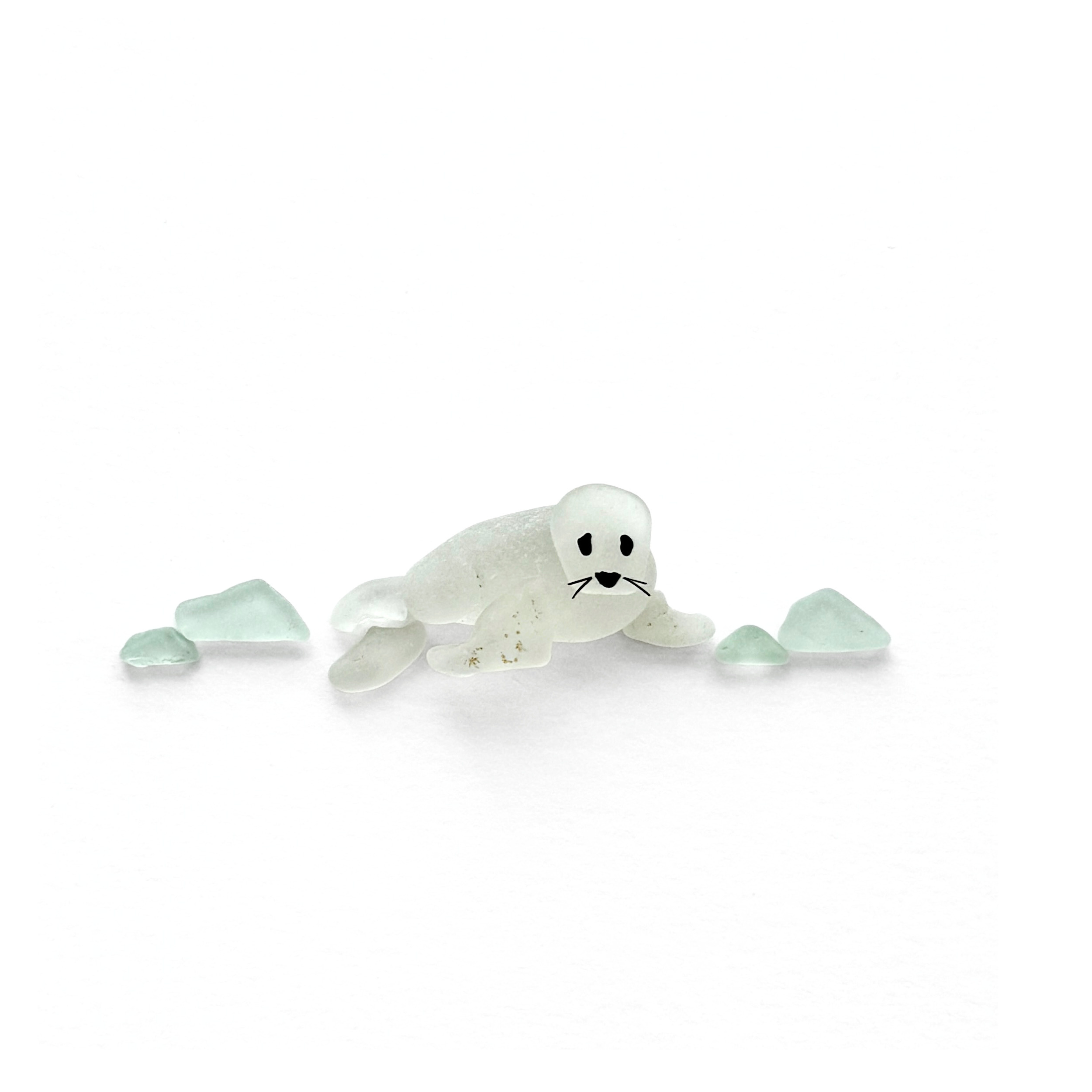 Baby harp seal resting among pale aqua sea glass in a minimalist coastal composition.
