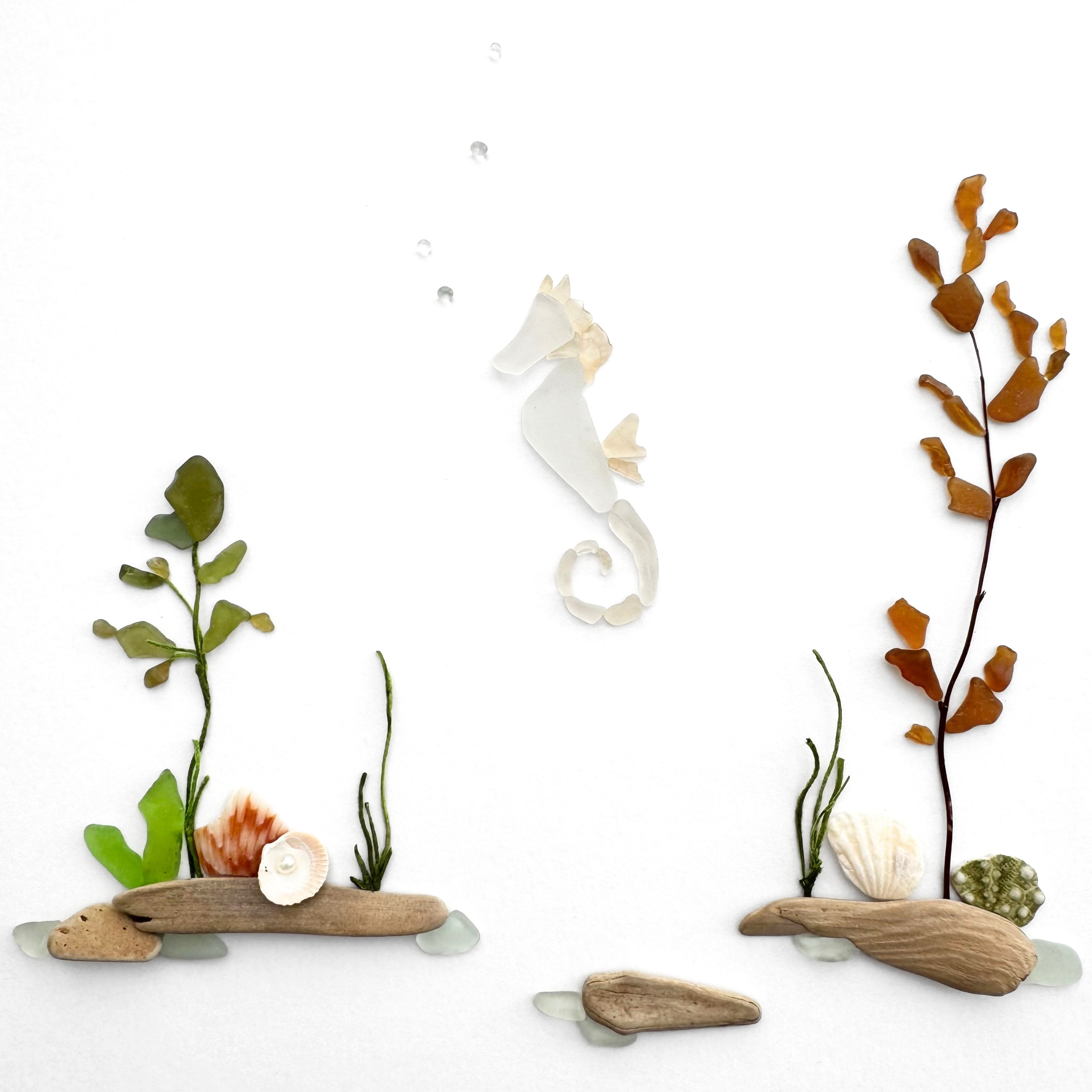 White sea glass seahorse floating between green and amber seaweed in a detailed underwater scene.
