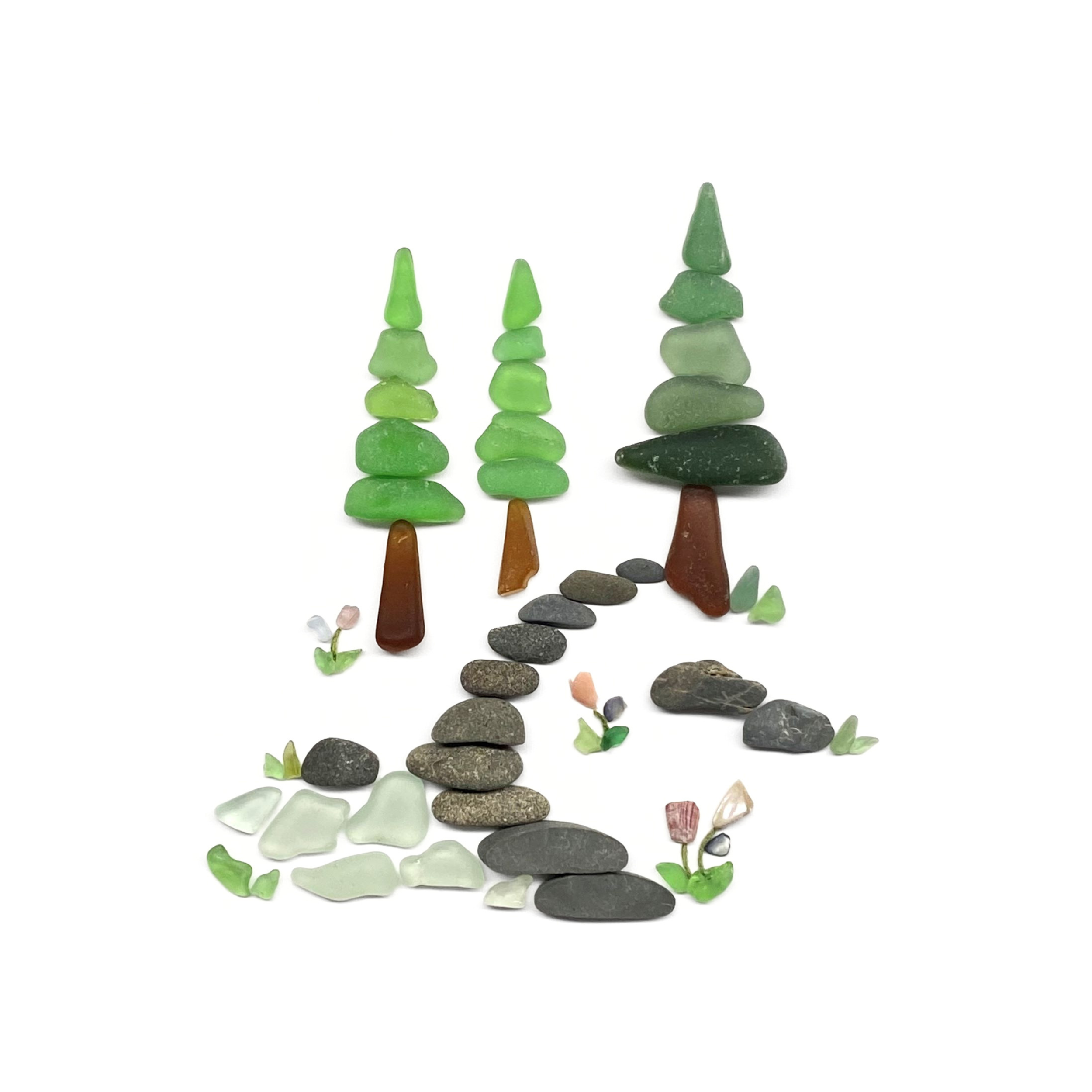 A woodland stream winds beneath evergreen trees, with smooth beach stones forming a path through the forest.