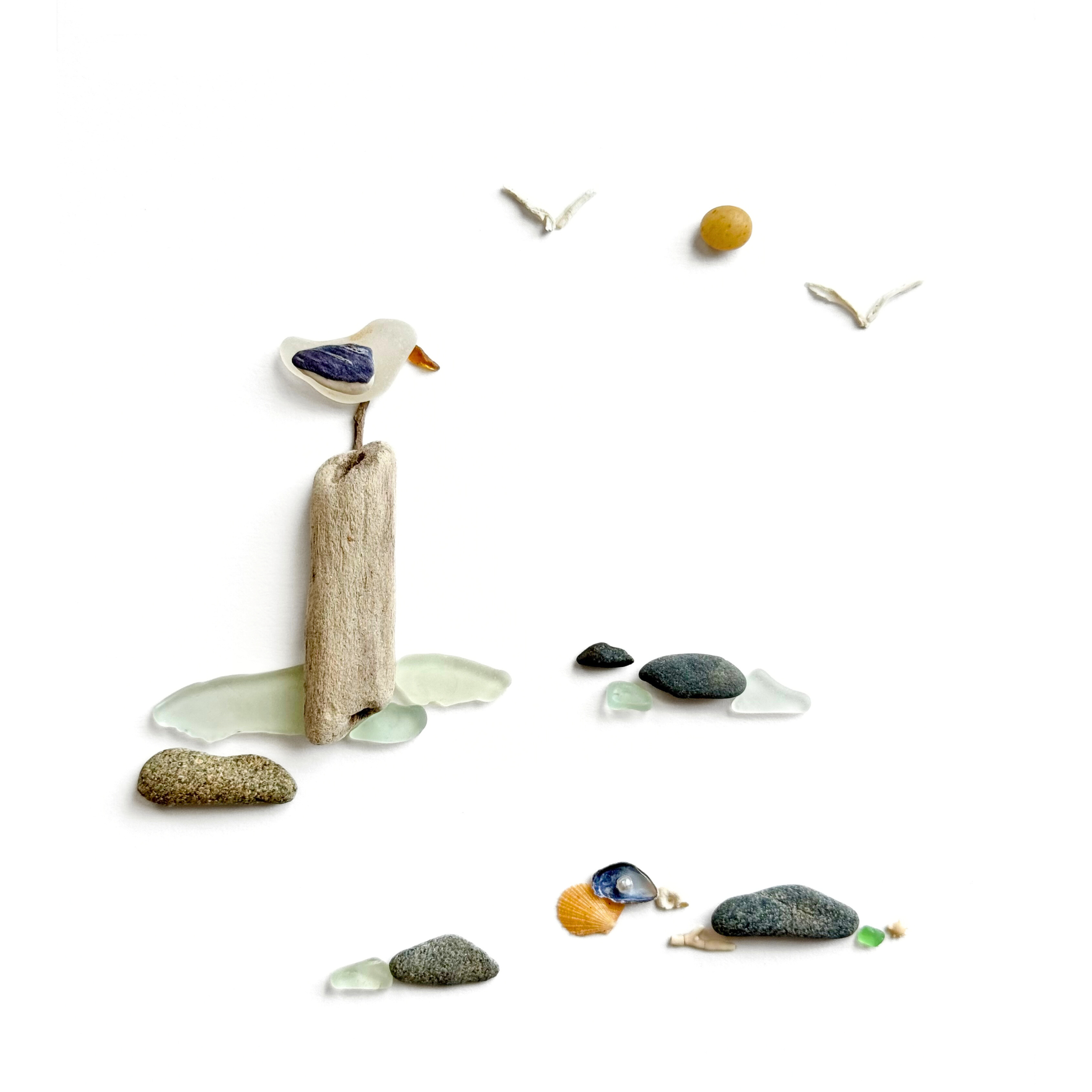 Seabird perched on weathered coastal driftwood above beach stones, shells, and sea glass.