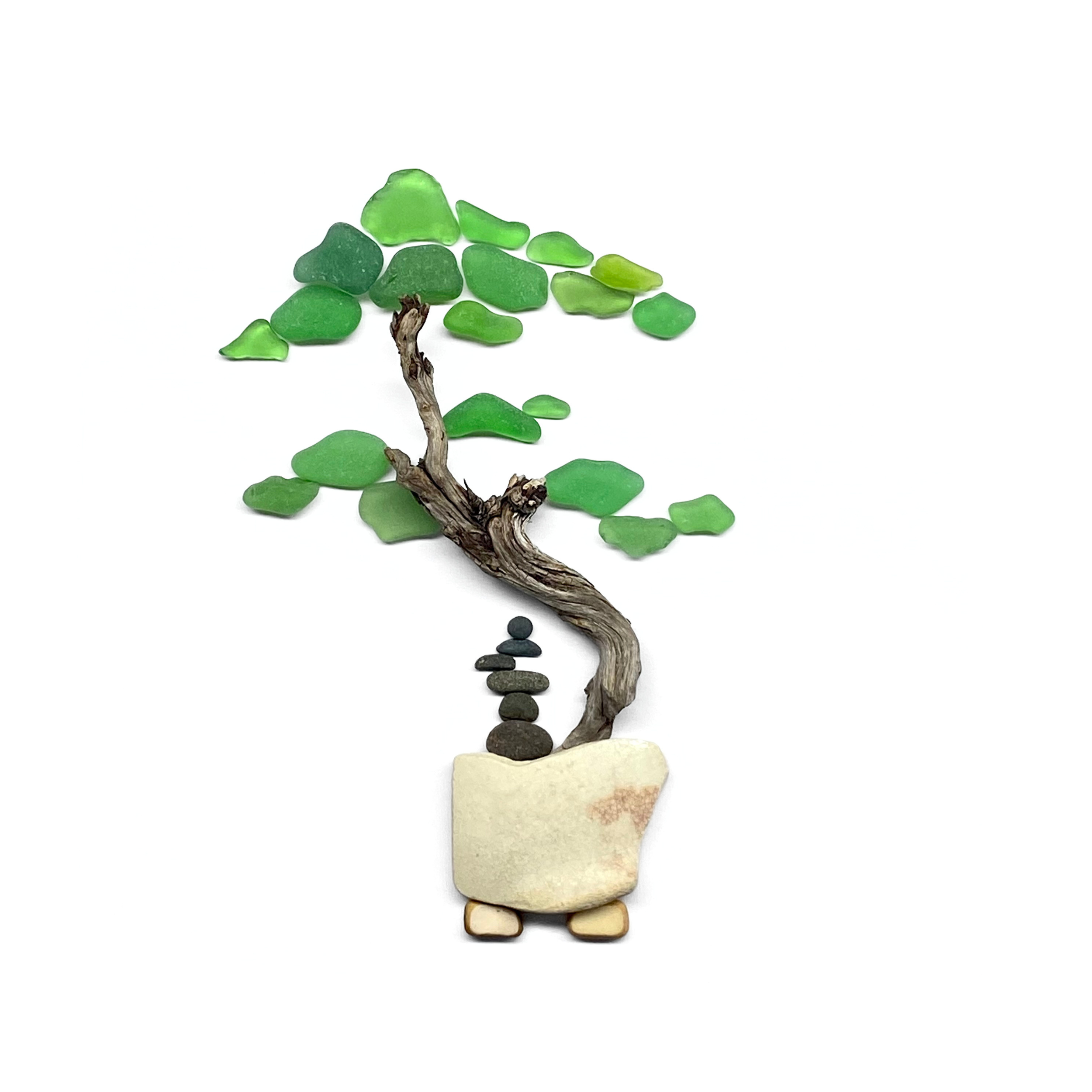 Sea glass bonsai tree with a twisted driftwood trunk in a small cream pottery planter with cairn stone stack.