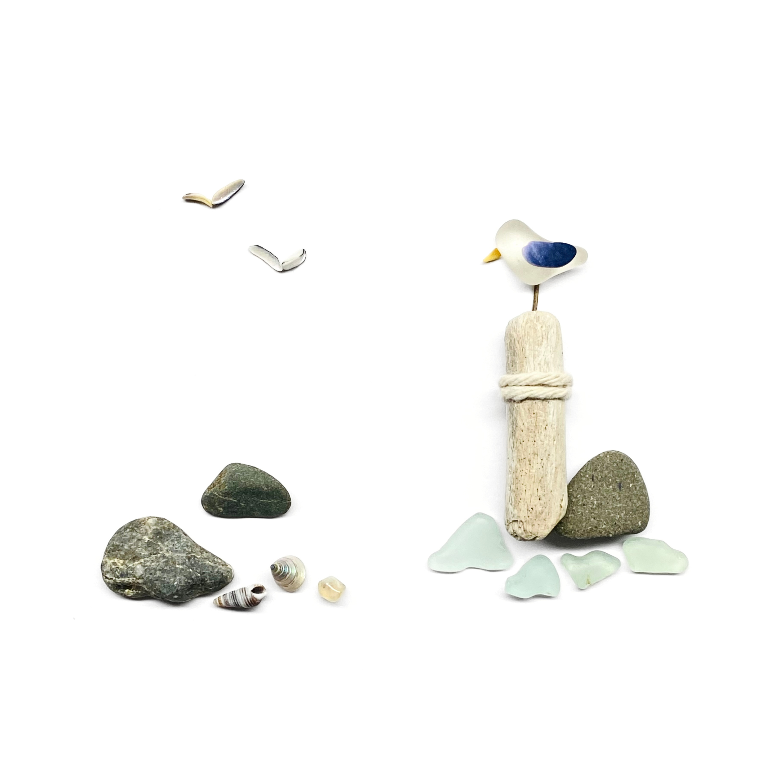 Seabird perched on a coastal buoy surrounded by sea glass, beach stones, and flying shell birds.
