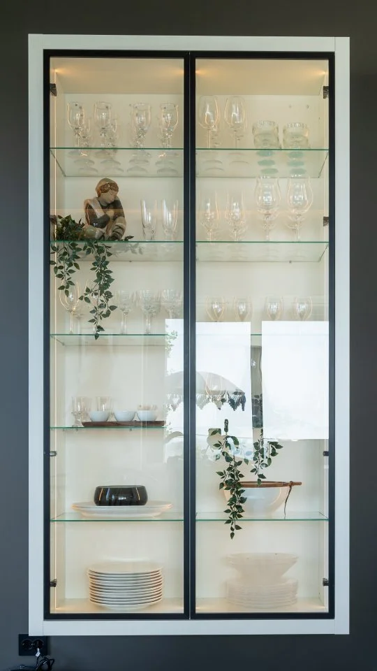 ✨ Et smykke til kjøkkenet! ✨ Glitre vitrineskapet kombinerer elegant design med funksjonalitet.
Den hvite omrammingen møter den slanke, sorte profilen på glassdøren, og innfelt belysning i skroget skaper en fin stemning. P