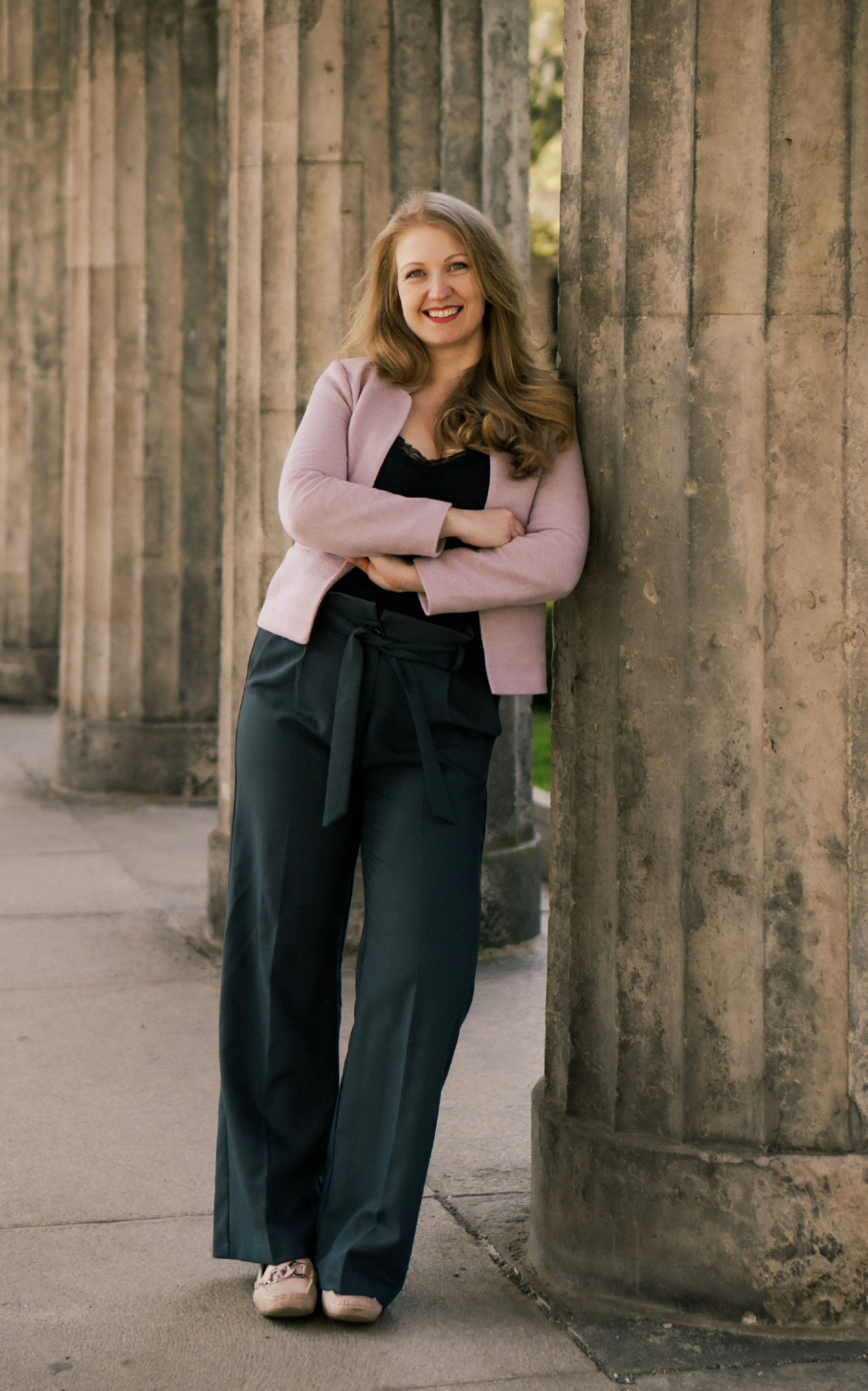 Alysia Tofflemire, founder of Alto Matchmaking, standing against a classical stone colonnade.
