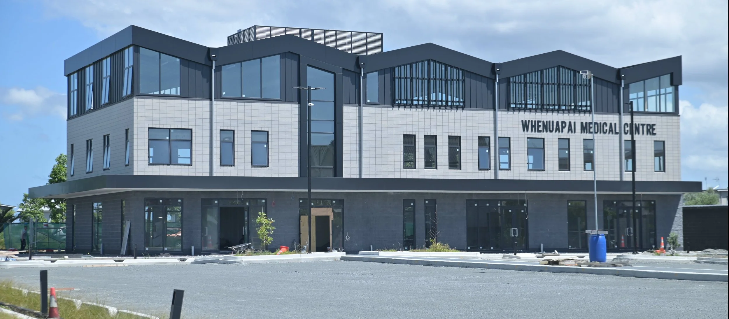 Exterior of Whenuapai Medical Centre building with glass windows and sign on the side.