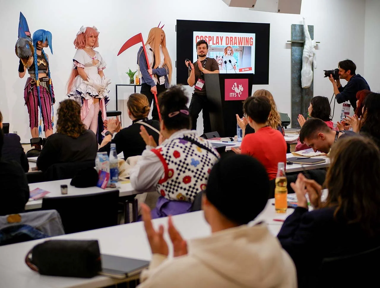 Menschen bei einer Cosplay-Veranstaltung, einige in Verkleidungen, einer auf der Bühne spricht, Kamera filmt, Publikum applaudiert in einem Konferenzraum.