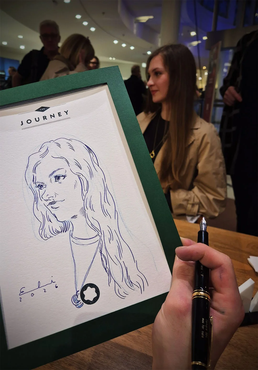 Zeichnung eines Mädchens mit langen, gewellten Haaren auf einem Papier, das in der Hand gehalten wird. Es scheint sich um eine Skizze im Stil eines Karikatur- oder Portraits zu handeln.