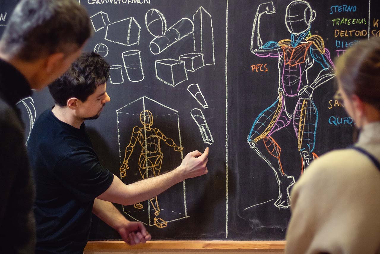 Lehrer erklärt eine Anatomietafel auf einer Tafel mit Skizzen von menschlichen Skeletten und Muskulatur, während Schüler zuschauen.
