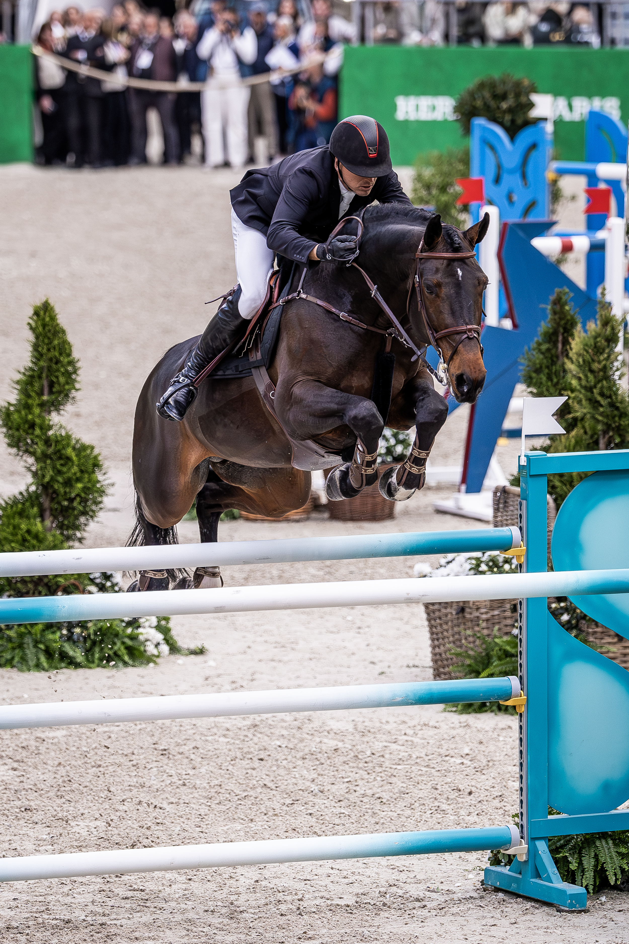 A horse and rider jumping over a hurdle in an equestrian show.