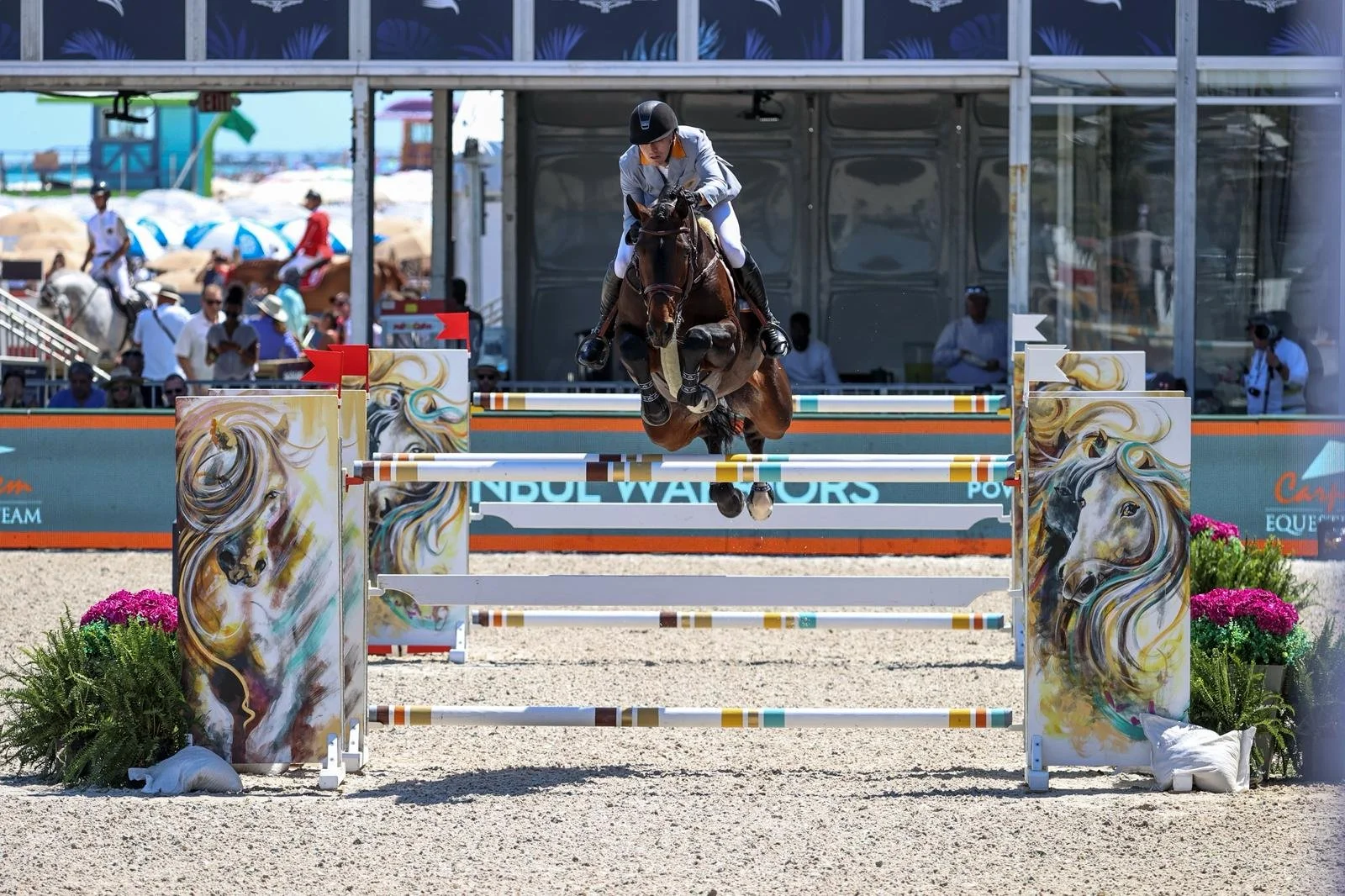 A horse and rider jumping over a show jumping obstacle at an equestrian event.