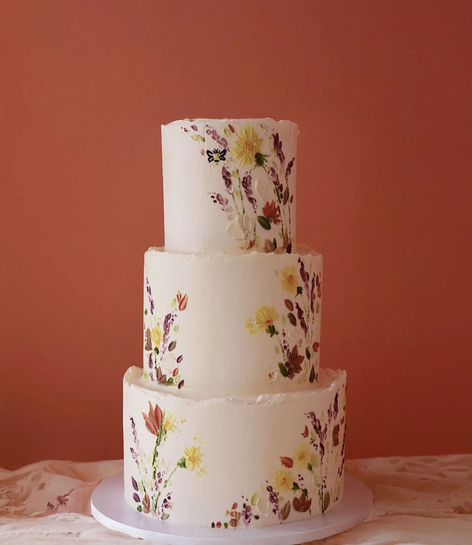 Three tier wedding cake with a natural and colourful wildflower theme, displayed in Somerset