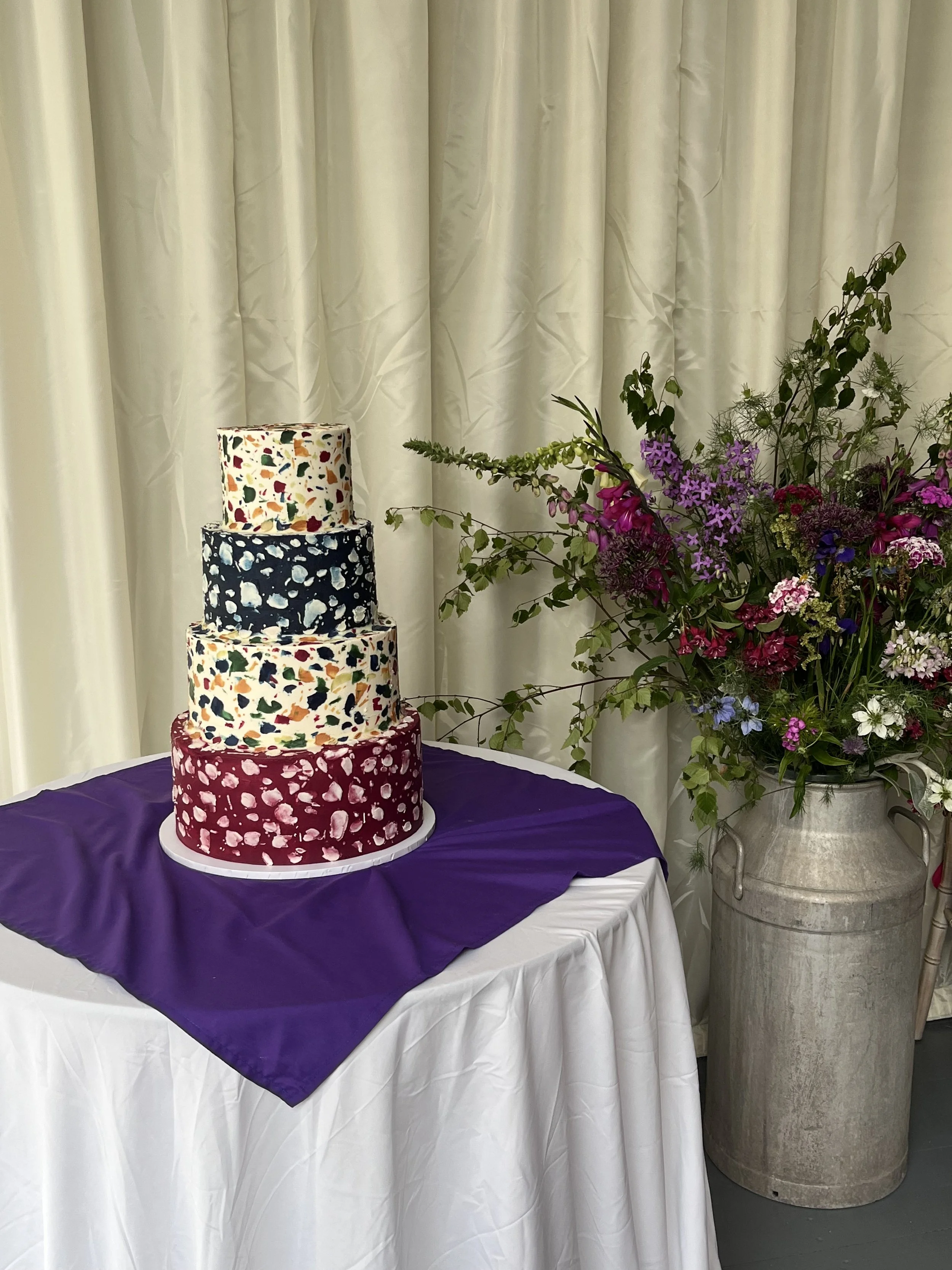 A four-tier vegan wedding cake with lots of colourful patterns in a Terrazzo style, displayed in Hampshire