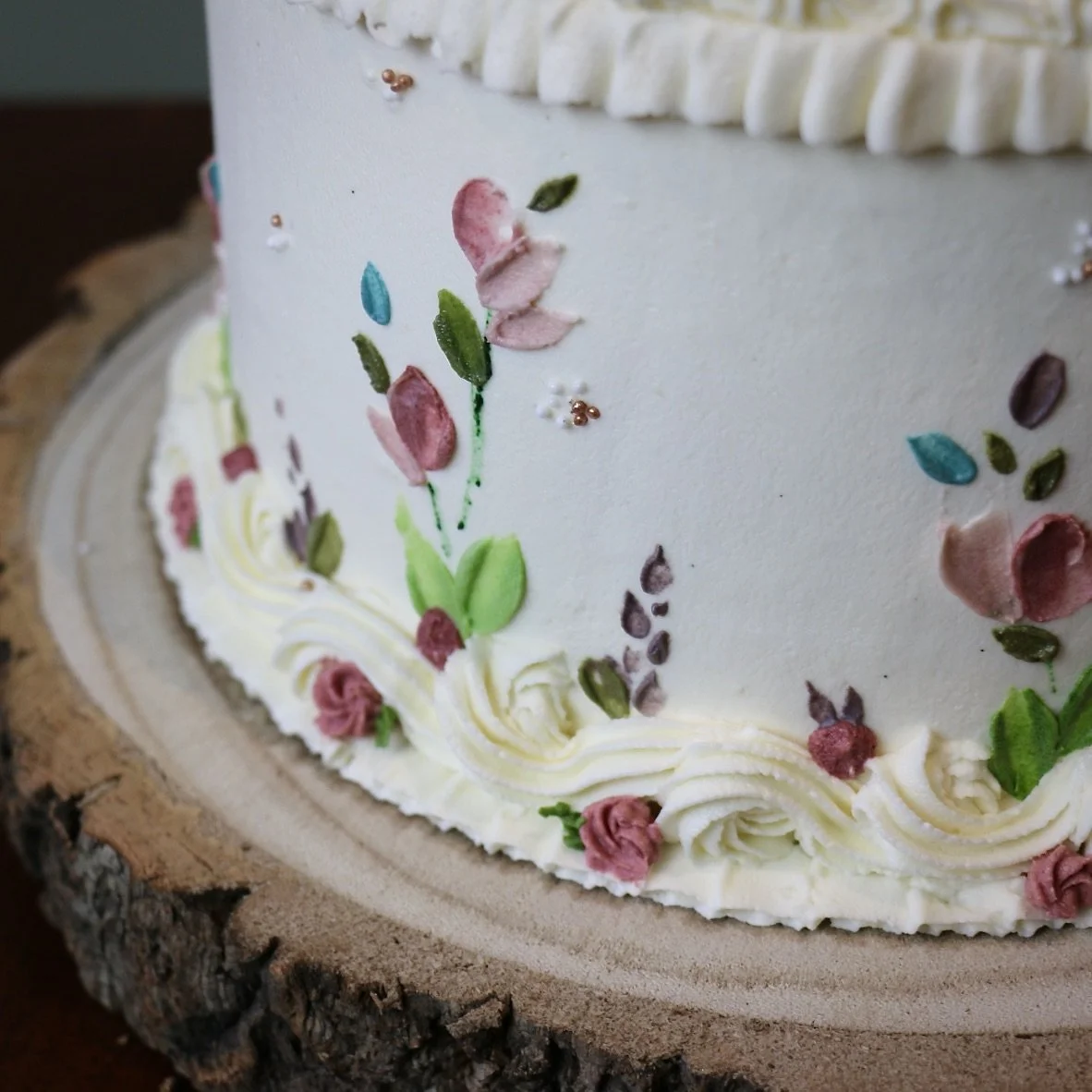 A white cake with vintage piping, piped roses and hand-painted flowers in muted tones