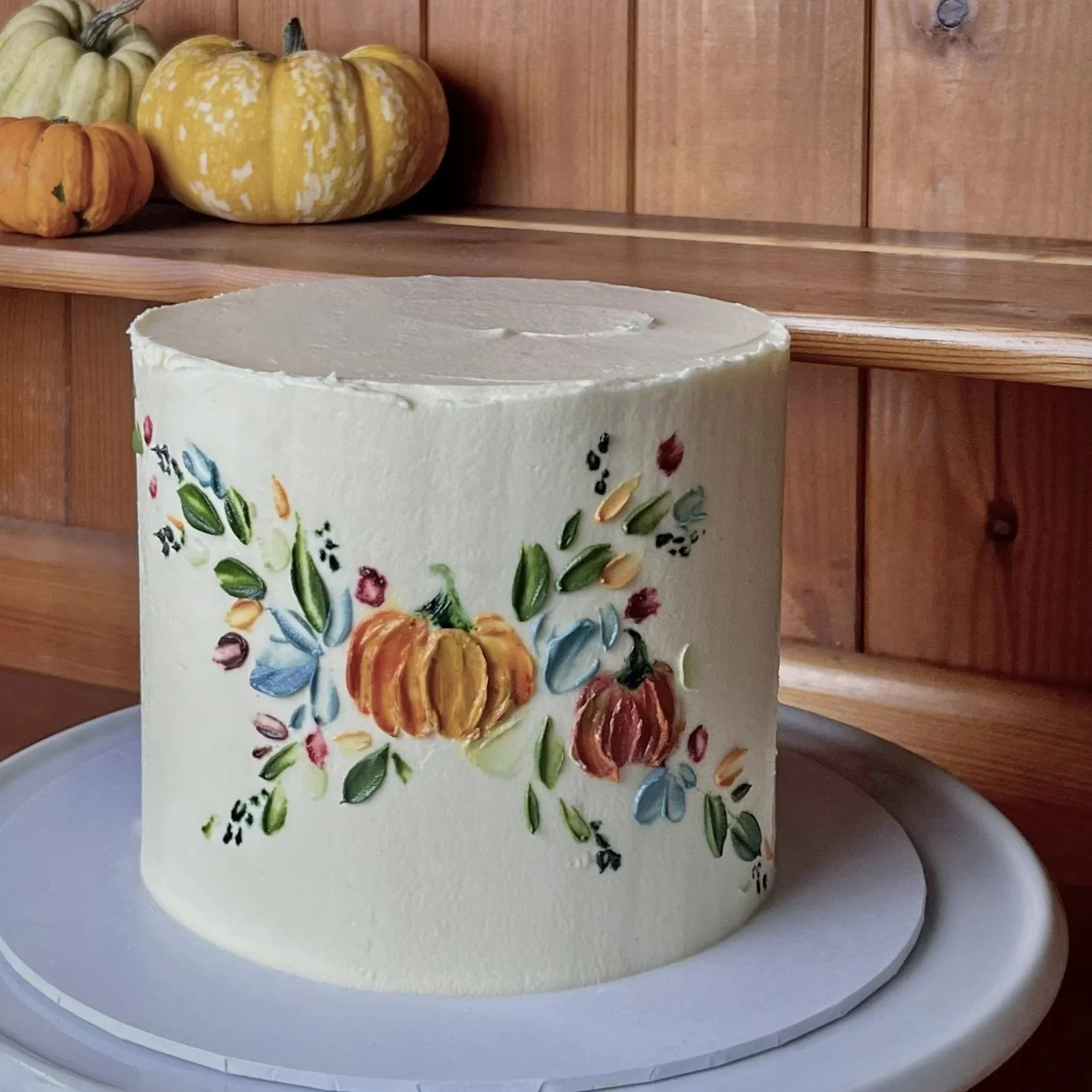 cream coloured cake with a pumpkin motif handpainted on the front buttercream