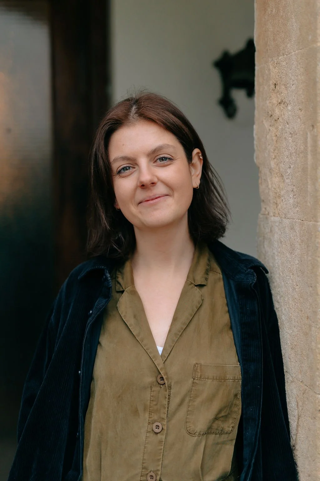 A cake designer leaning against a stone wall.