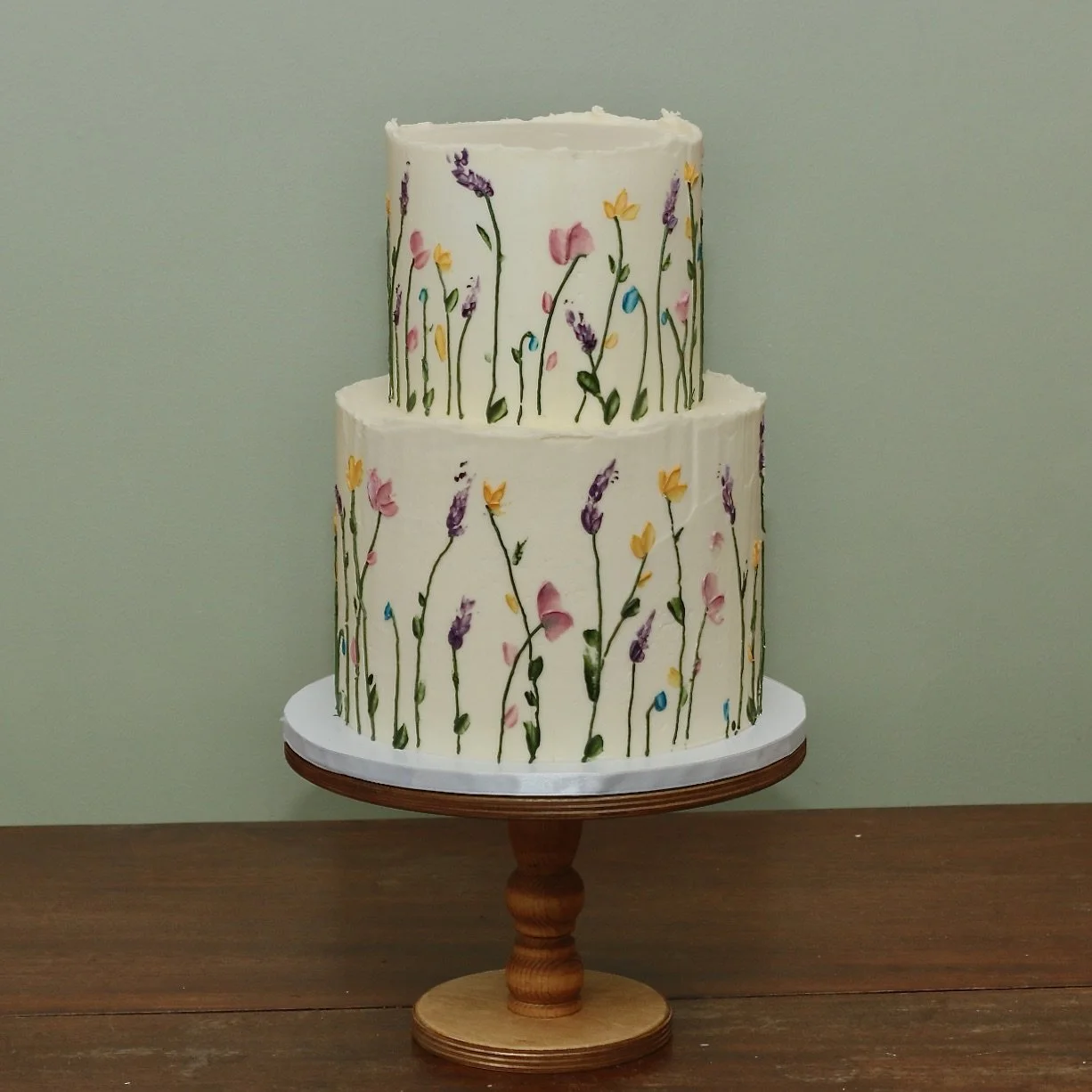 two tier wedding cake with a meadow design flowing around the sides with colourful flowers and lavender