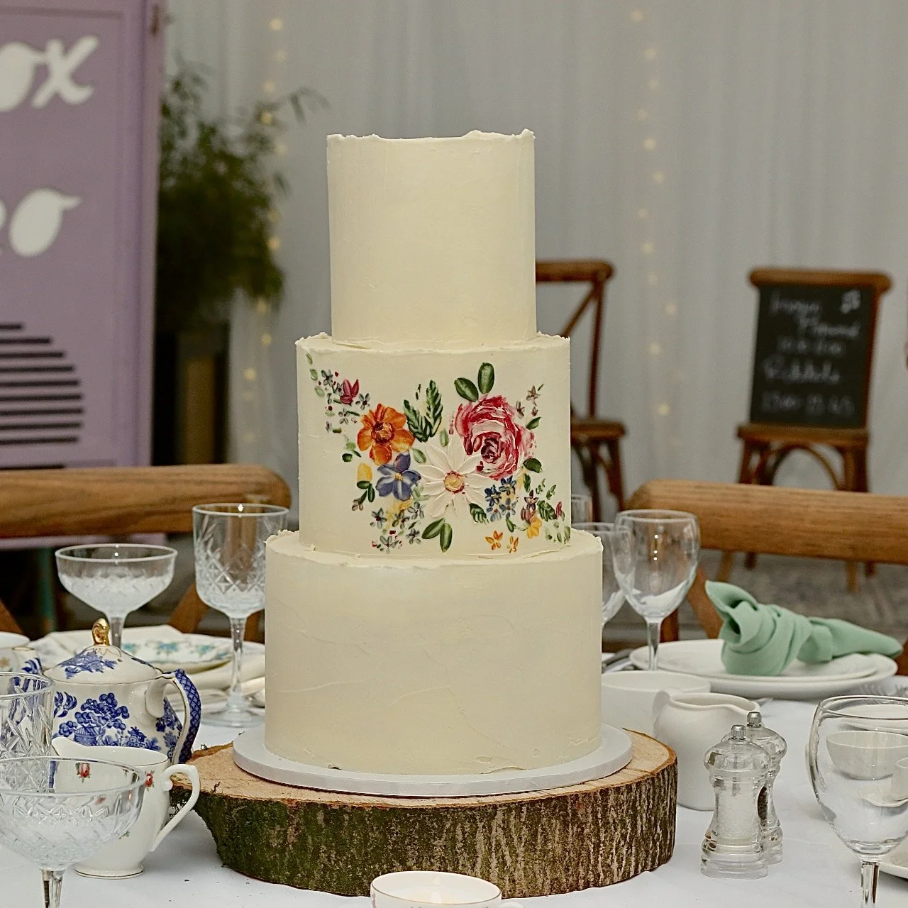 floral wedding cake with central painted motif