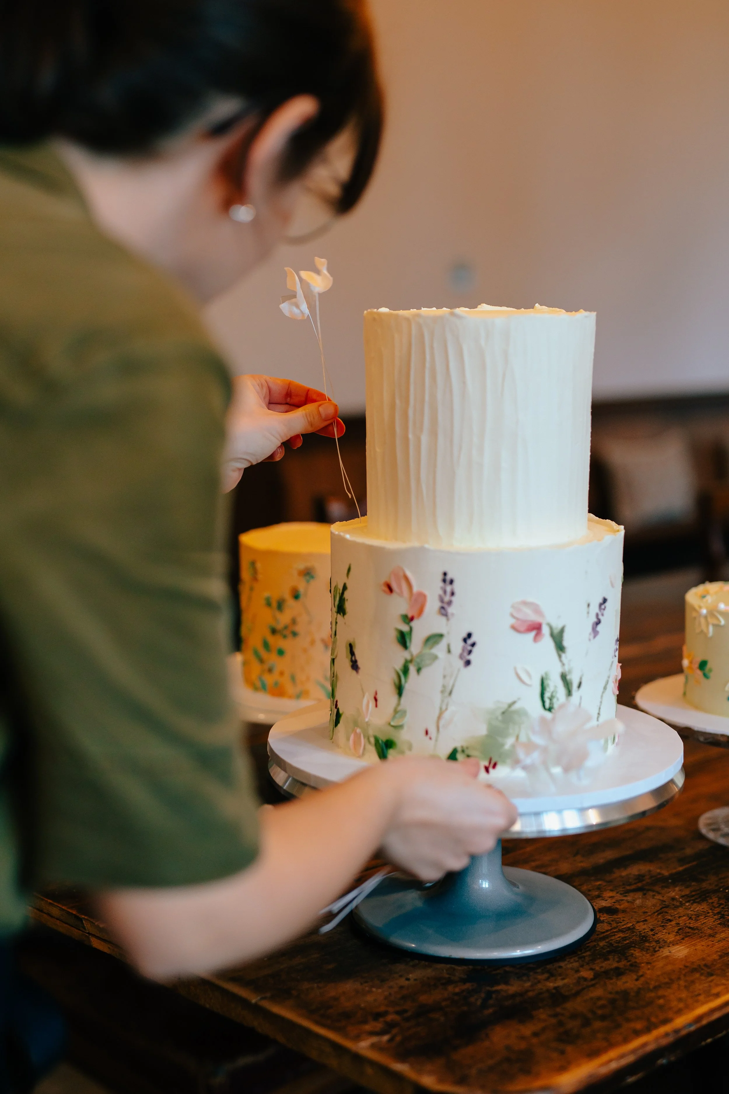 A vegan cake designer setting up a wedding cake in Bristol with floral detailing and nature inspired designs
