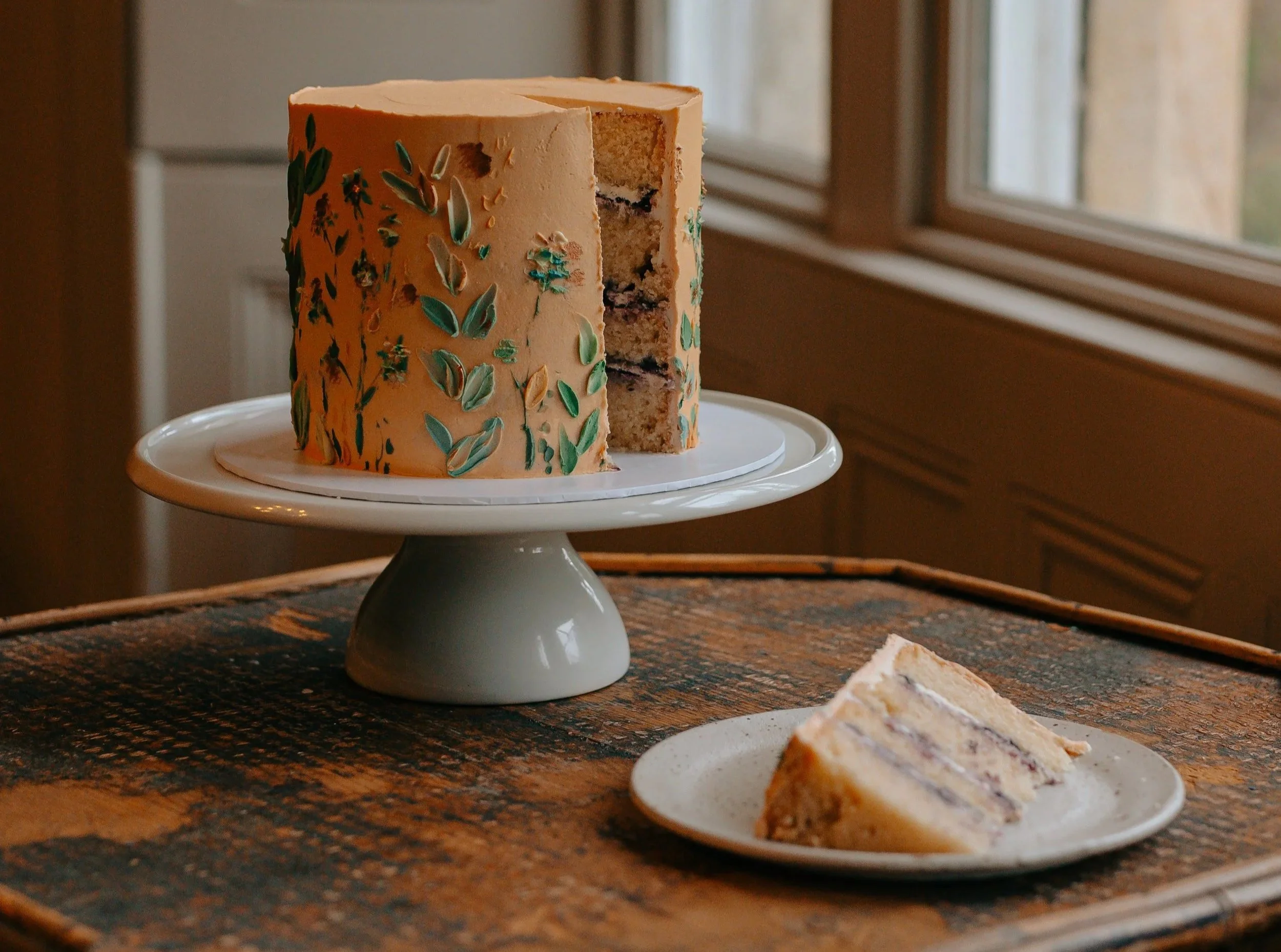 a orange celebration cake covered in a nature inspired theme with four layers of vanilla sponge and blueberry jam