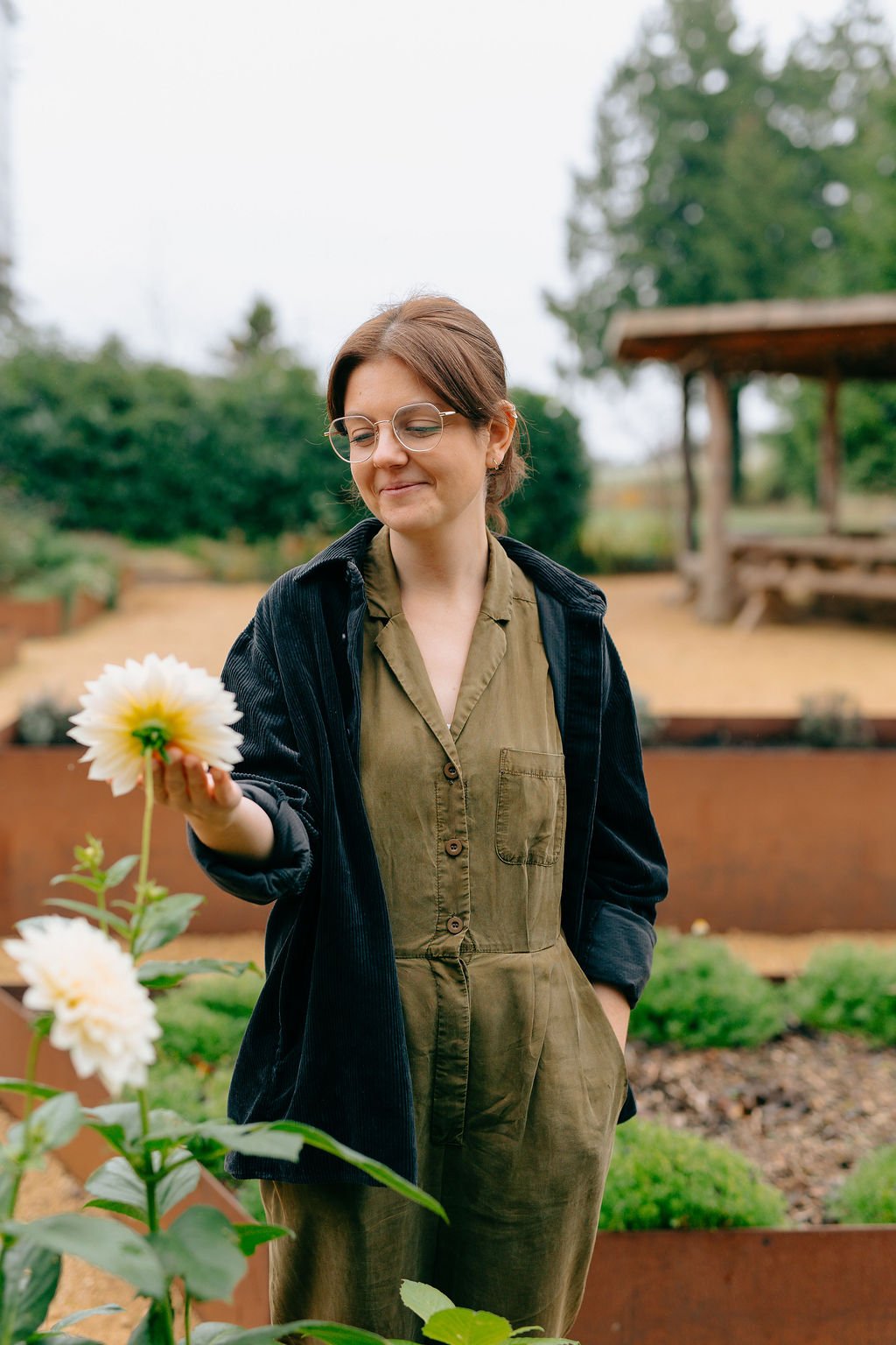 A vegan cake designer looking at some dahlias in a natural open space