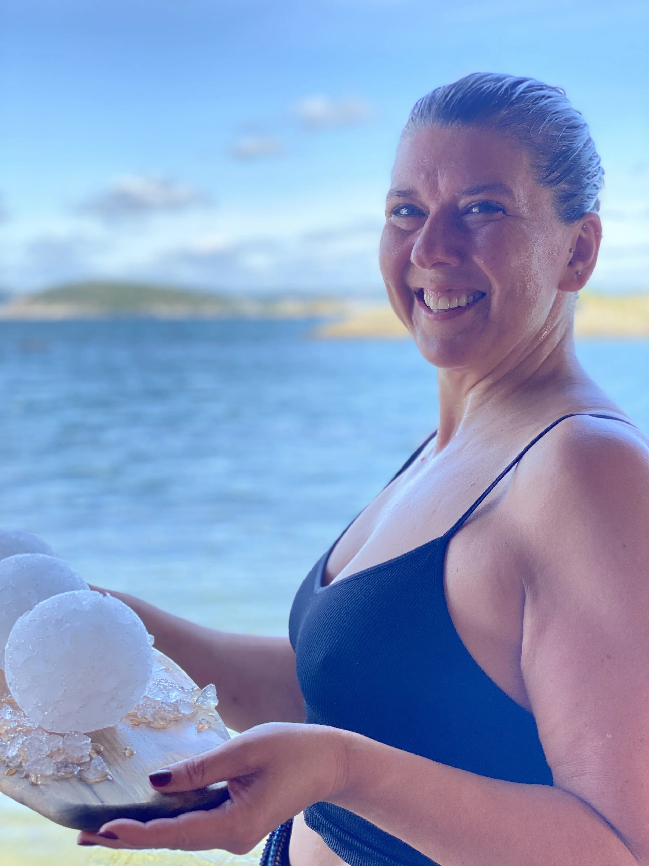 En blid kvinne stående utenfor en sauna ved stranden