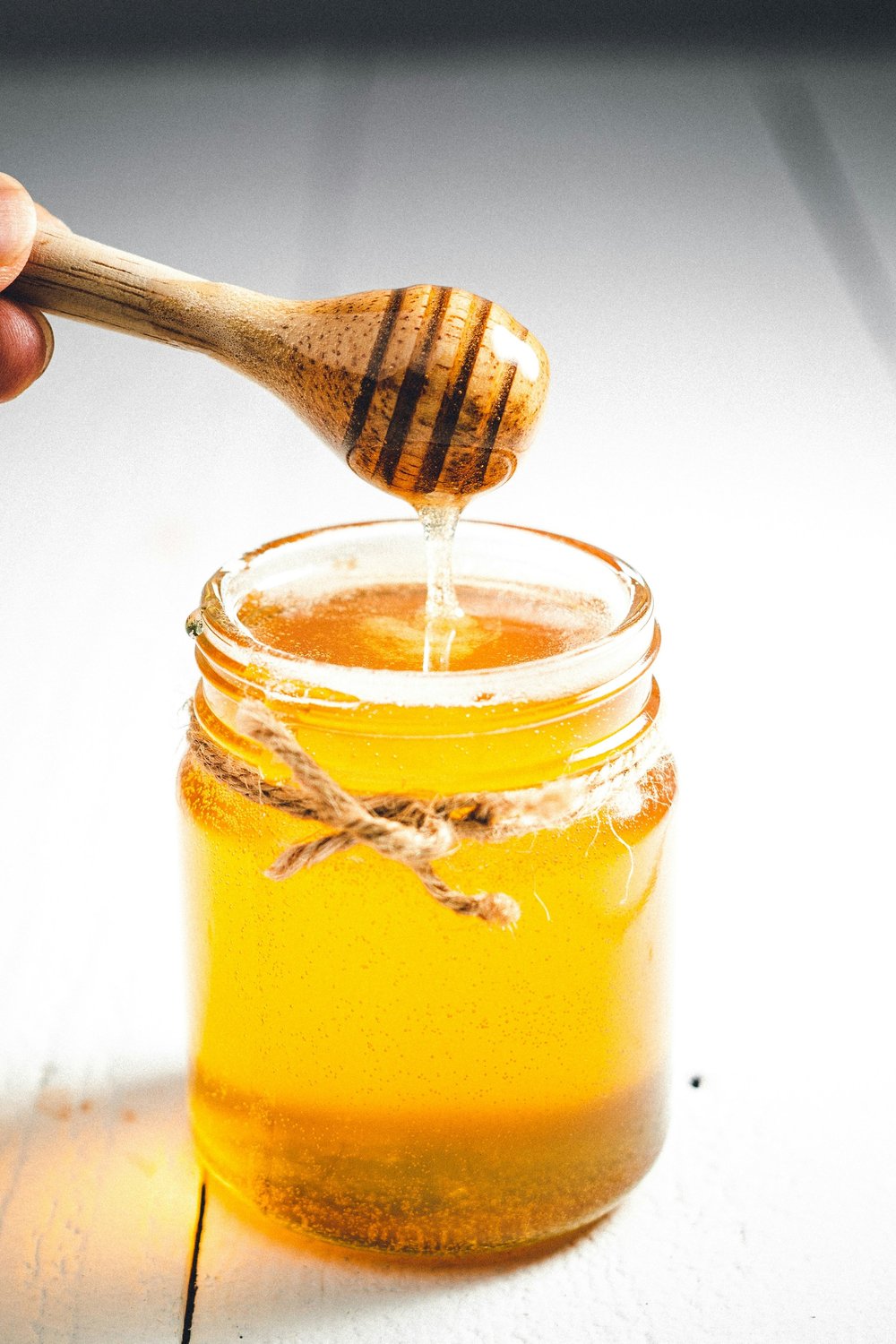 A jar of honey with a wooden honey dipper