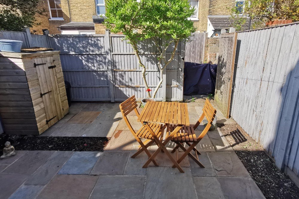 Two rope-and-oak lounge chairs beside a corten steel water bowl in a Twickenham courtyard garden, with granite paving and cottage-style planting. Built by vladthelandscaper.co.uk.

A pair of Kettler lounge chairs sit on light grey granite paving in t