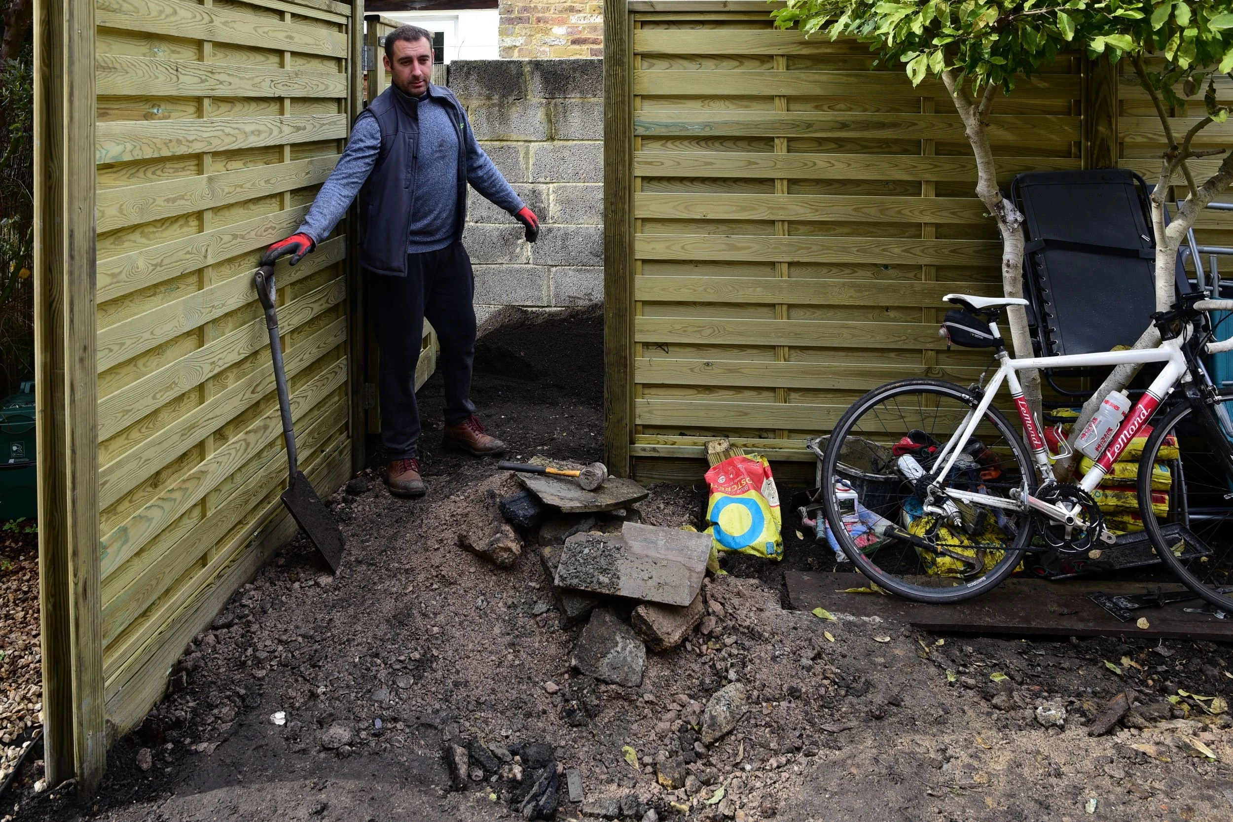 Vlad the Landscaper on site during construction of a Twickenham courtyard garden, surrounded by tools and building materials.

A behind-the-scenes look at the courtyard mid-build, with the new timber fencing freshly installed but the ground still bar
