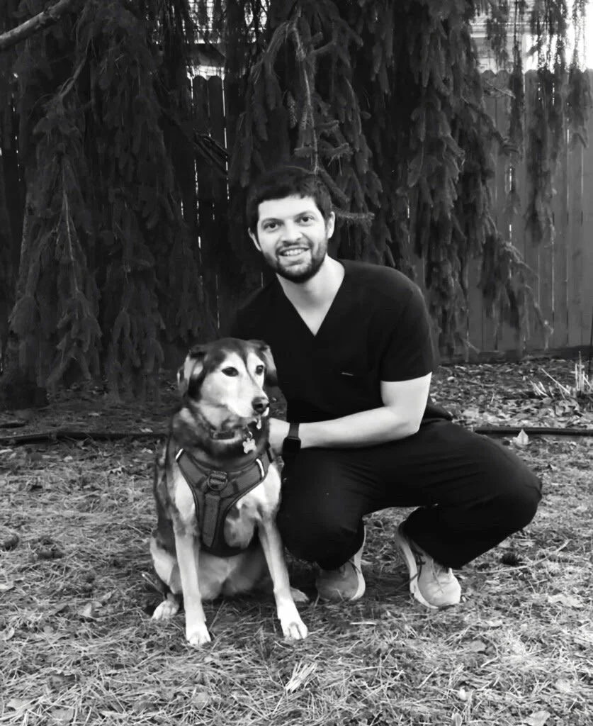 Dr. Mike McAllion squatting in grass with mixed breed dog black and white photo