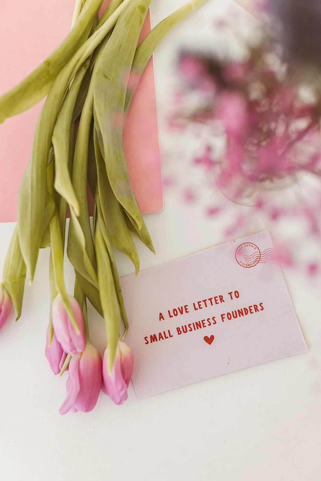 Pink tulips next to an envelope with red text "A love letter to small business founders."