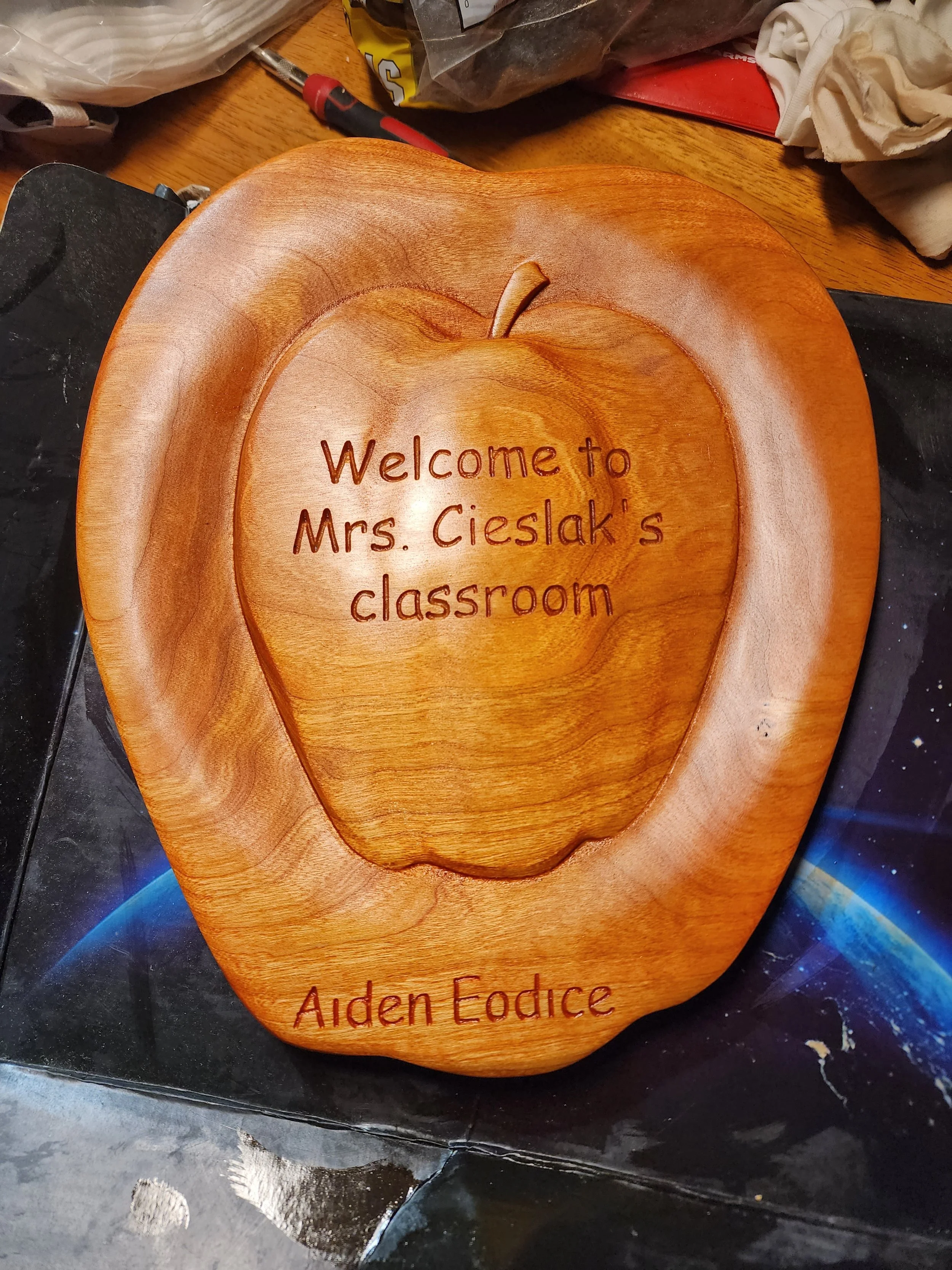 Wooden plaque shaped like a pumpkin with engraved text that reads 'Welcome to Mrs. Cieslak's classroom' and 'Aiden Eodice'.