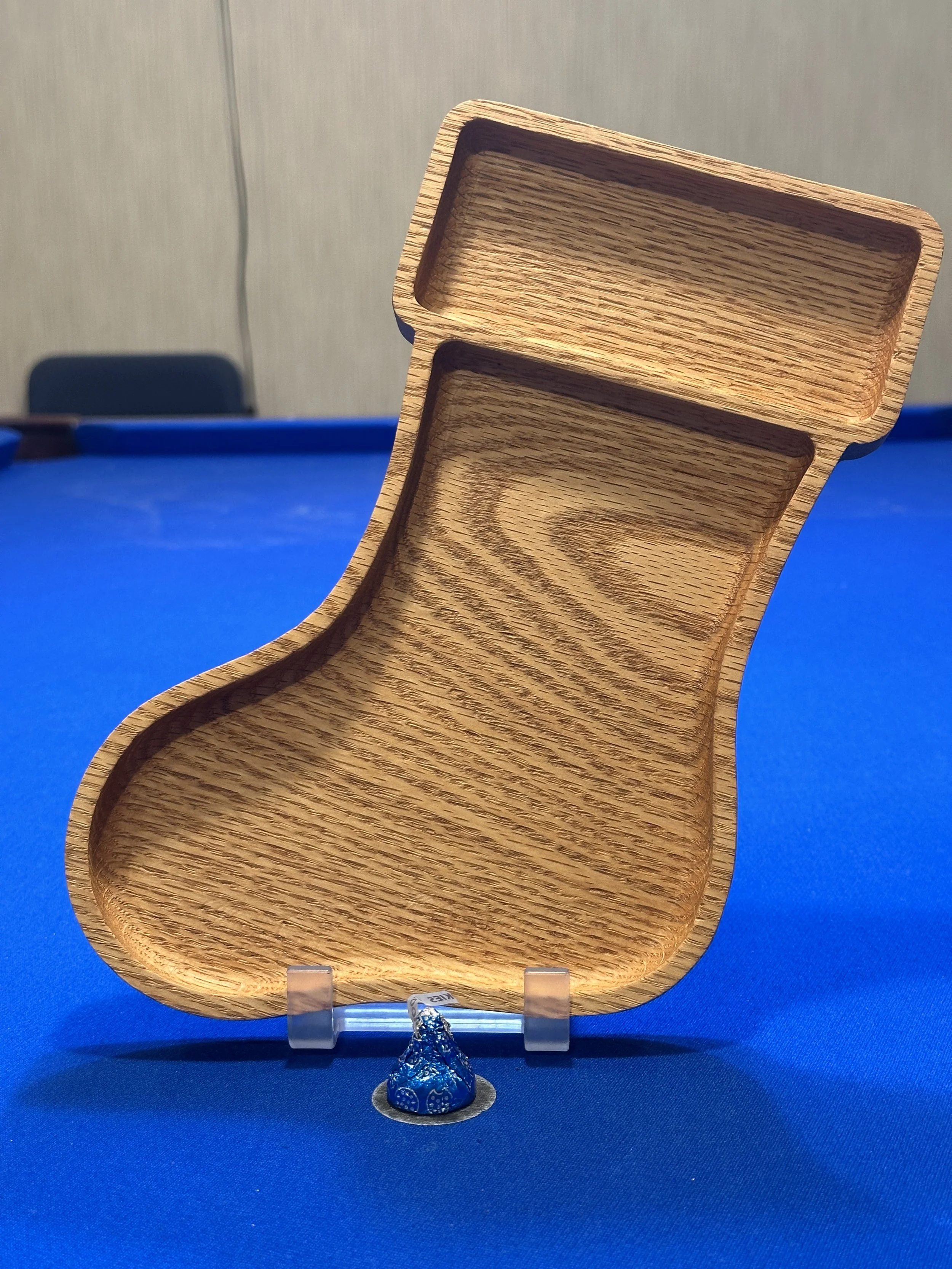 A wooden opened box with compartments displayed on a blue surface, with a small wrapped object in front.