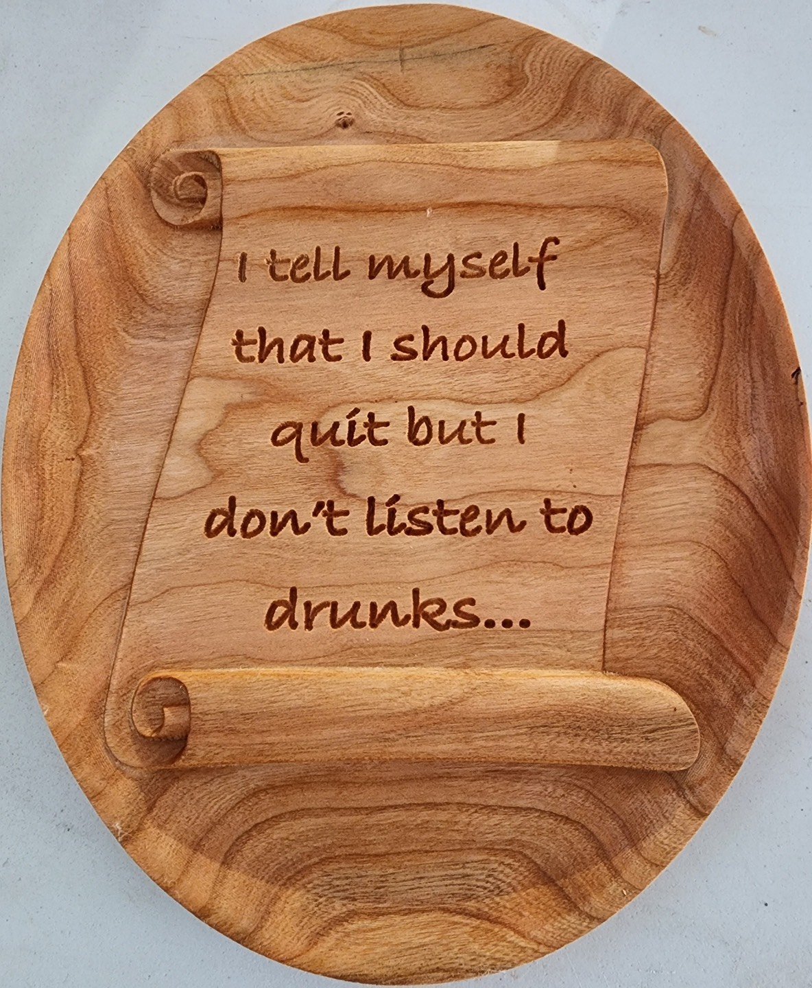 A wooden plaque with a scroll design, inscribed with the phrase: "I tell myself that I should quit but I don't listen to drunks..."