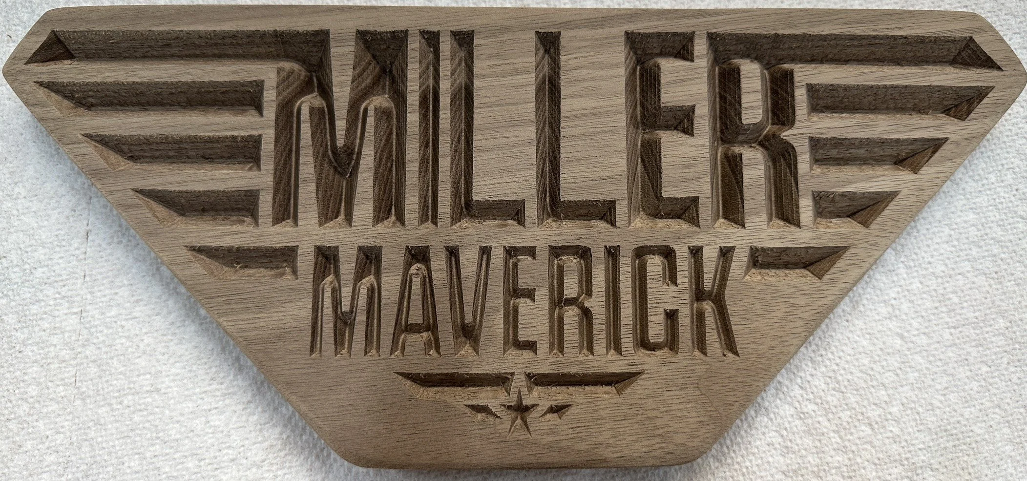 Wooden block with the words "Never Forget" and "Menuvecik" carved into it, featuring a star symbol underneath.