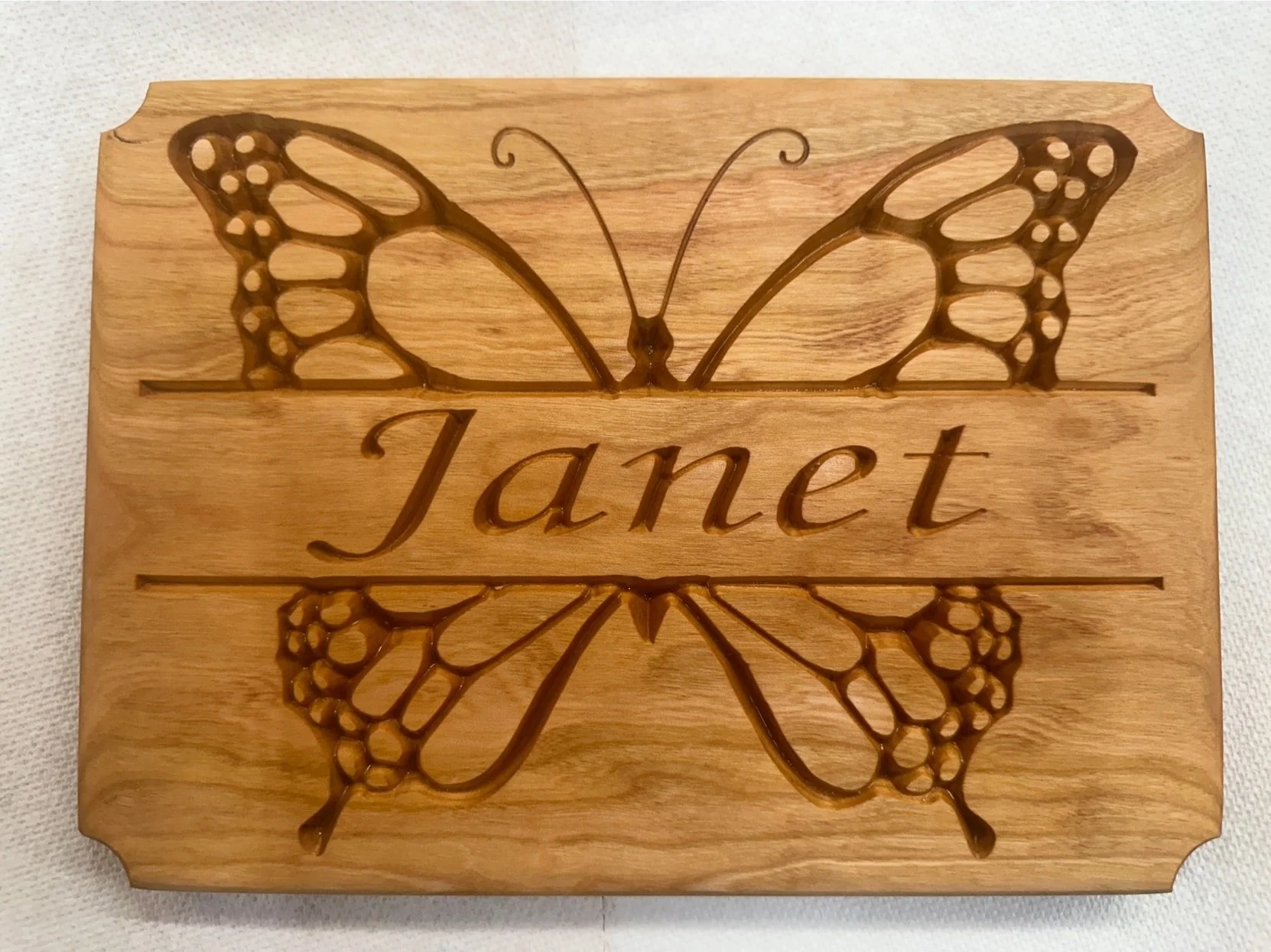 Wooden wall decor featuring a butterfly with the name "Janet" engraved in the center.