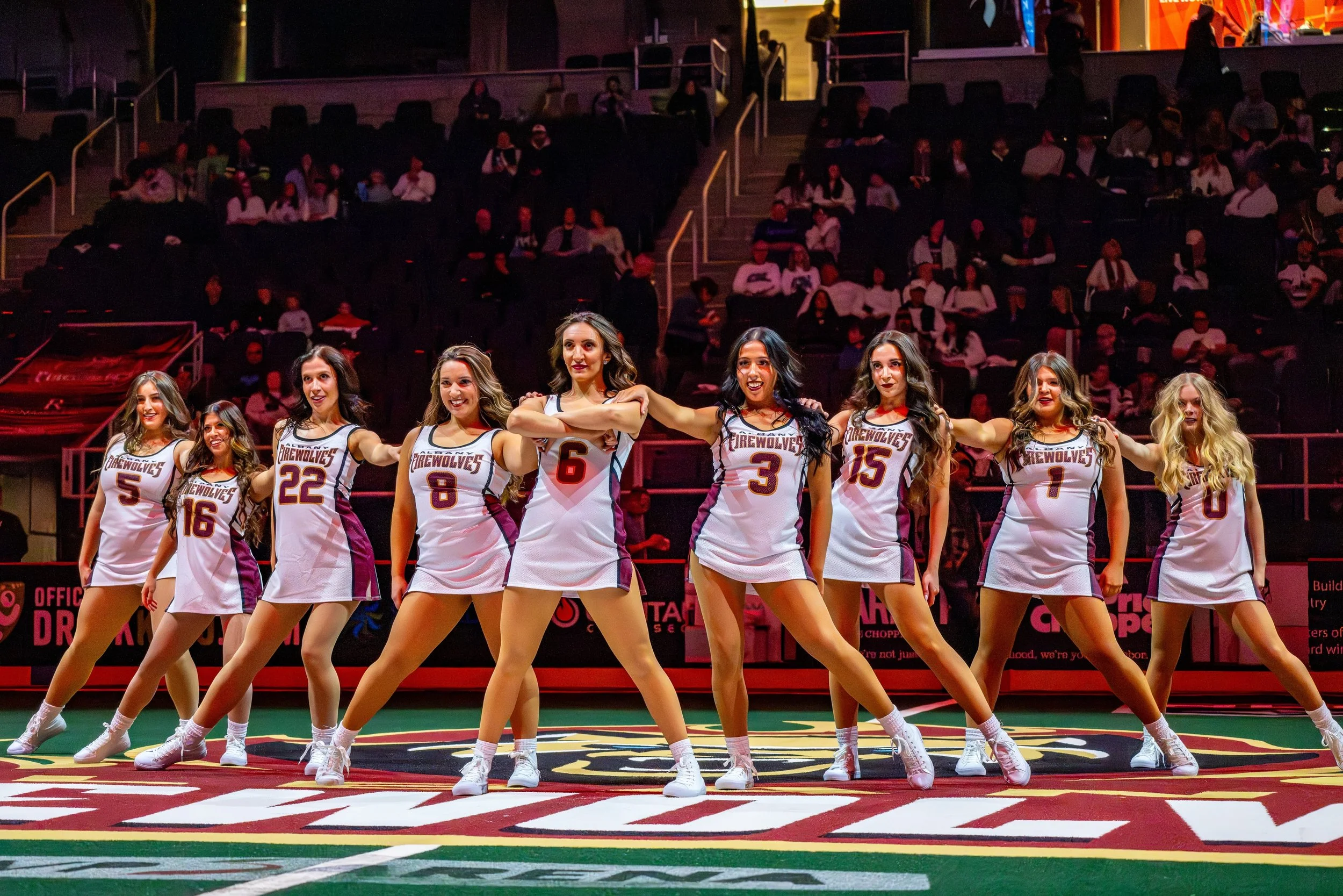 Group of women basketball players in white jerseys dancing on a basketball court.