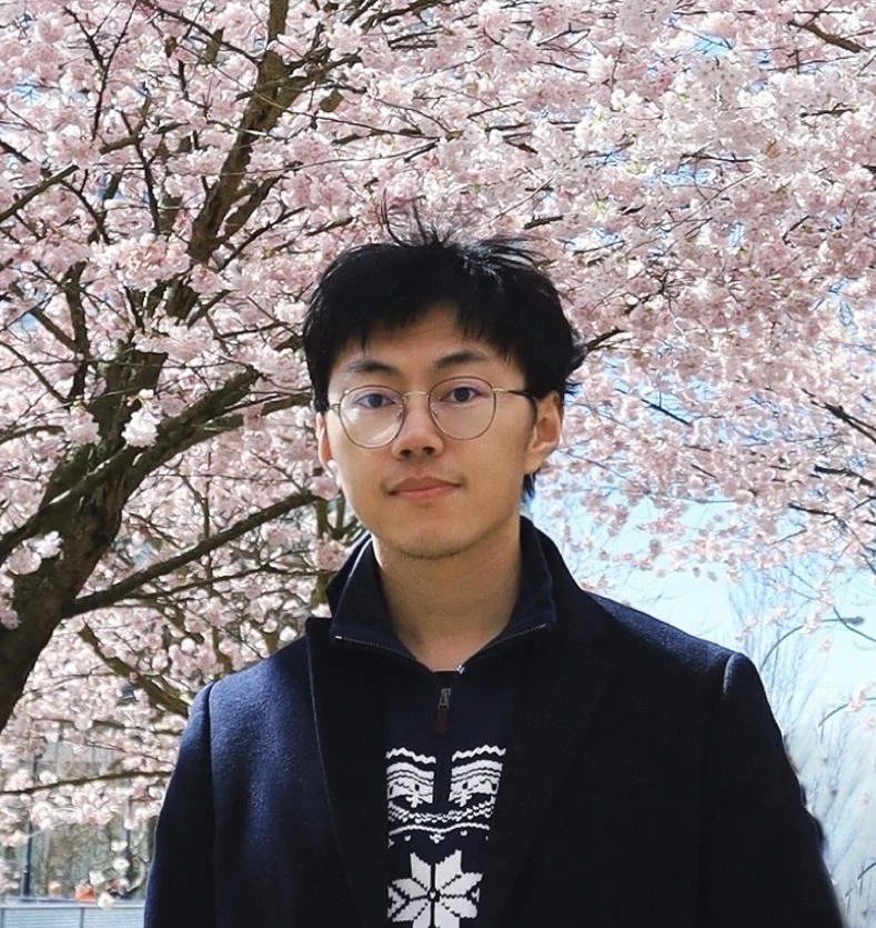 Yi (Joshua) Ren standing in front of tree blossom
